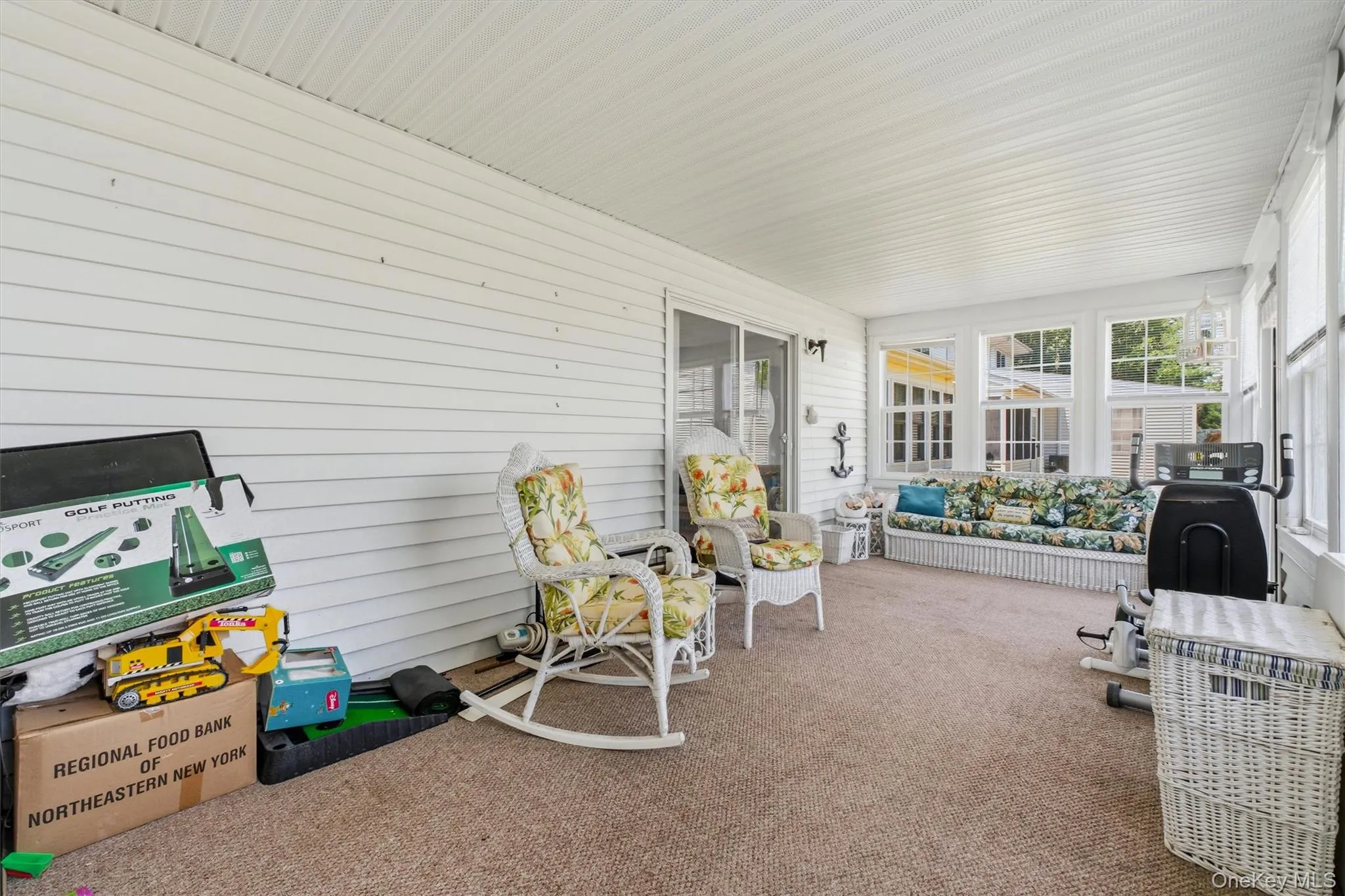 Enclosed porch featuring multiple windows, white vinyl siding, textured carpet, and a sliding glass door Enclosed porch featuring multiple windows, white vinyl siding, textured carpet, and a sliding glass door