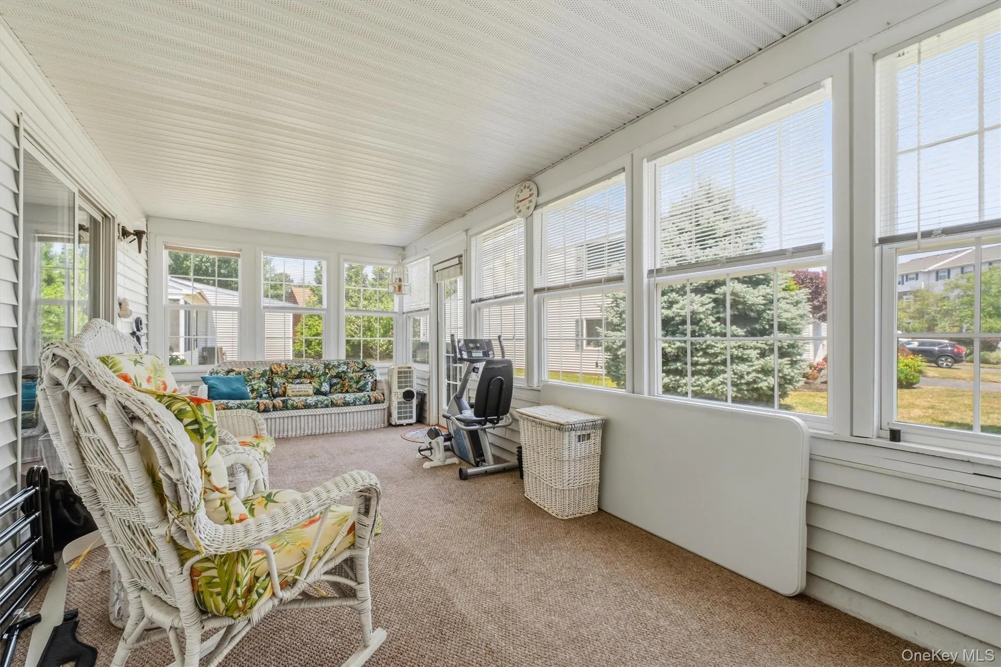 Spacious sunroom featuring multiple windows, a carpeted floor, and a paneled ceiling Spacious sunroom featuring multiple windows, a carpeted floor, and a paneled ceiling