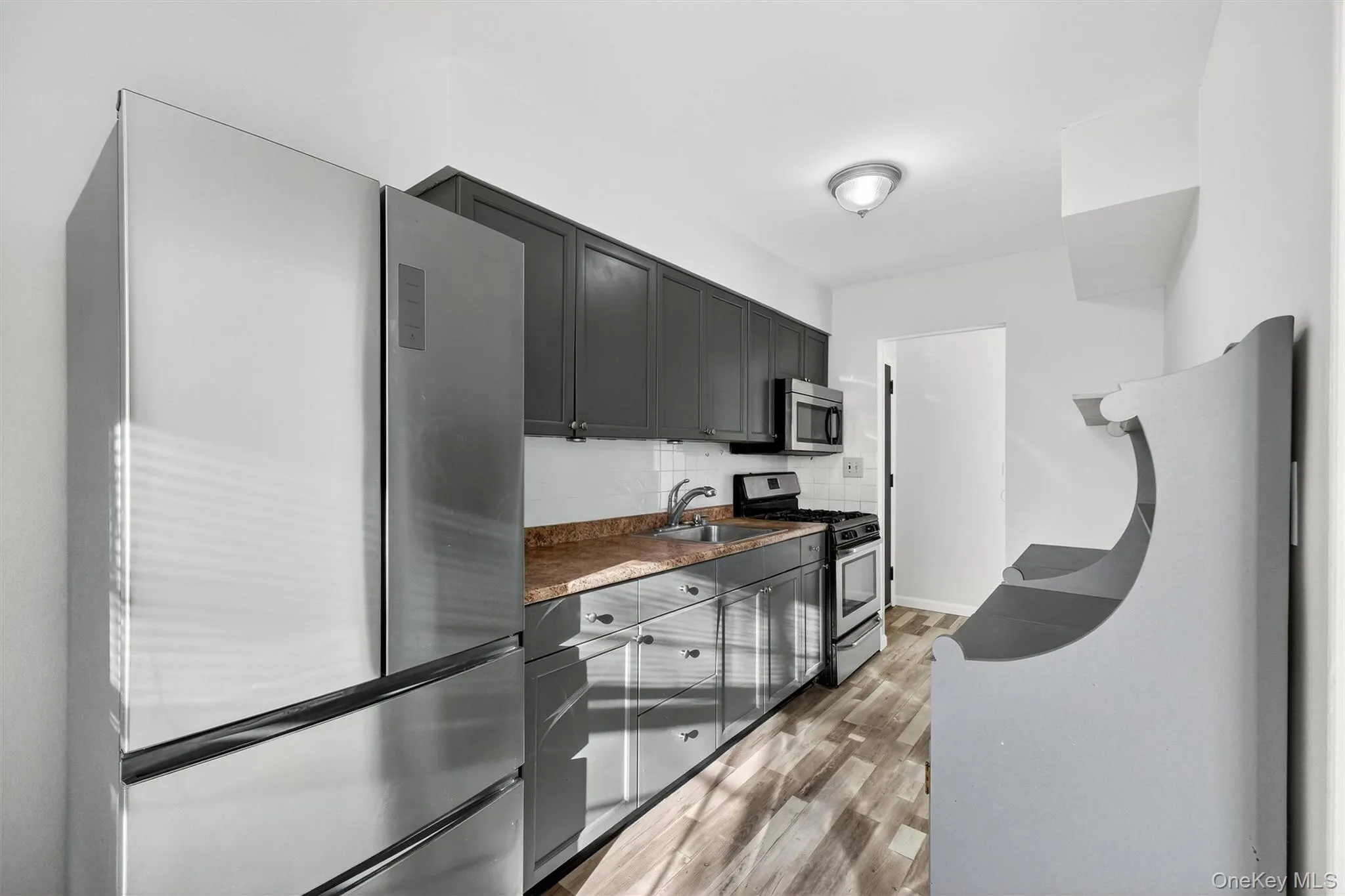 Kitchen with stainless steel appliances, tasteful backsplash, dark countertops, and gray cabinets Kitchen with stainless steel appliances, tasteful backsplash, dark countertops, and gray cabinets