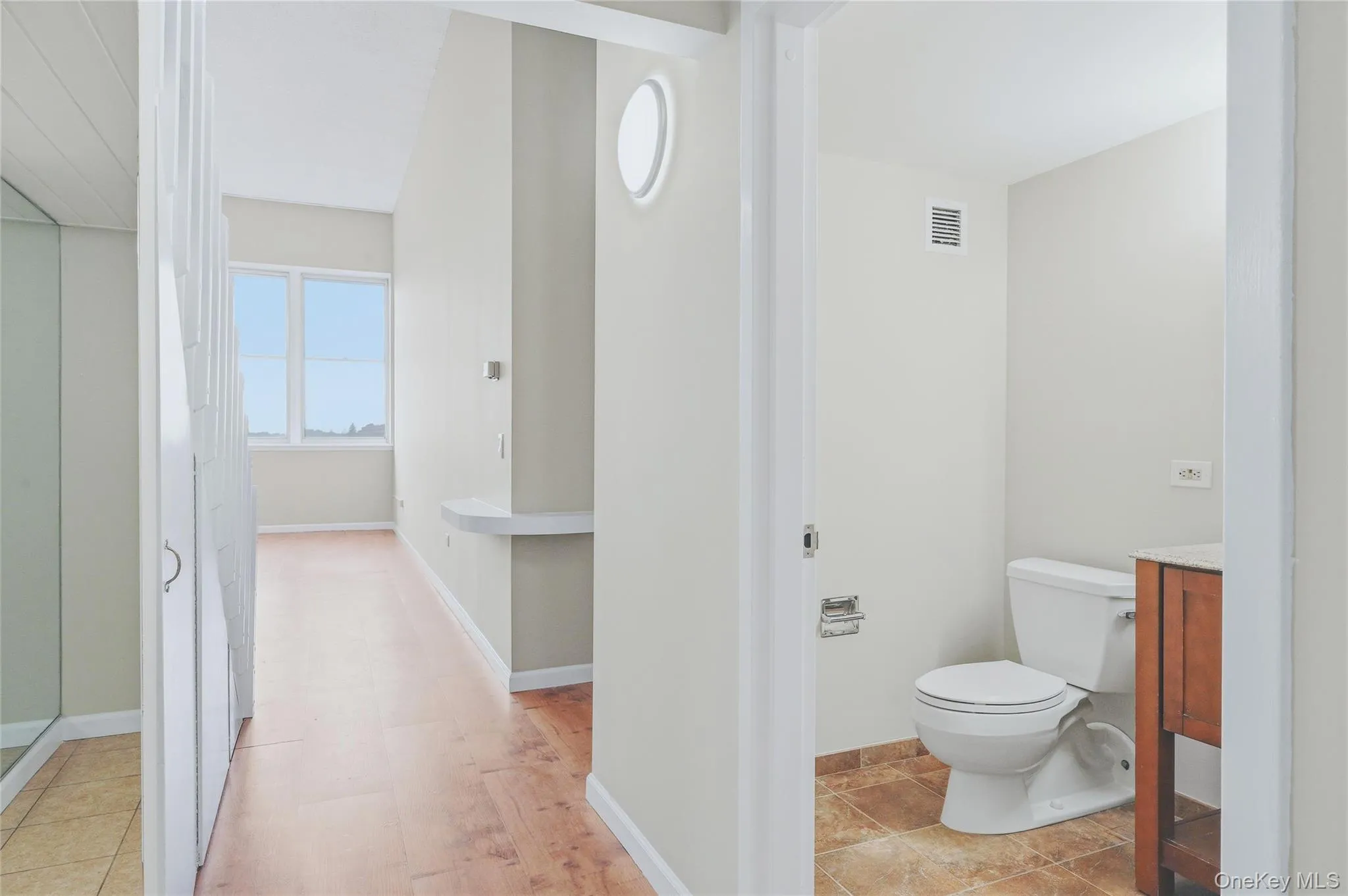 Hallway with view into full bathroom and living room. Hallway with view into full bathroom and living room.