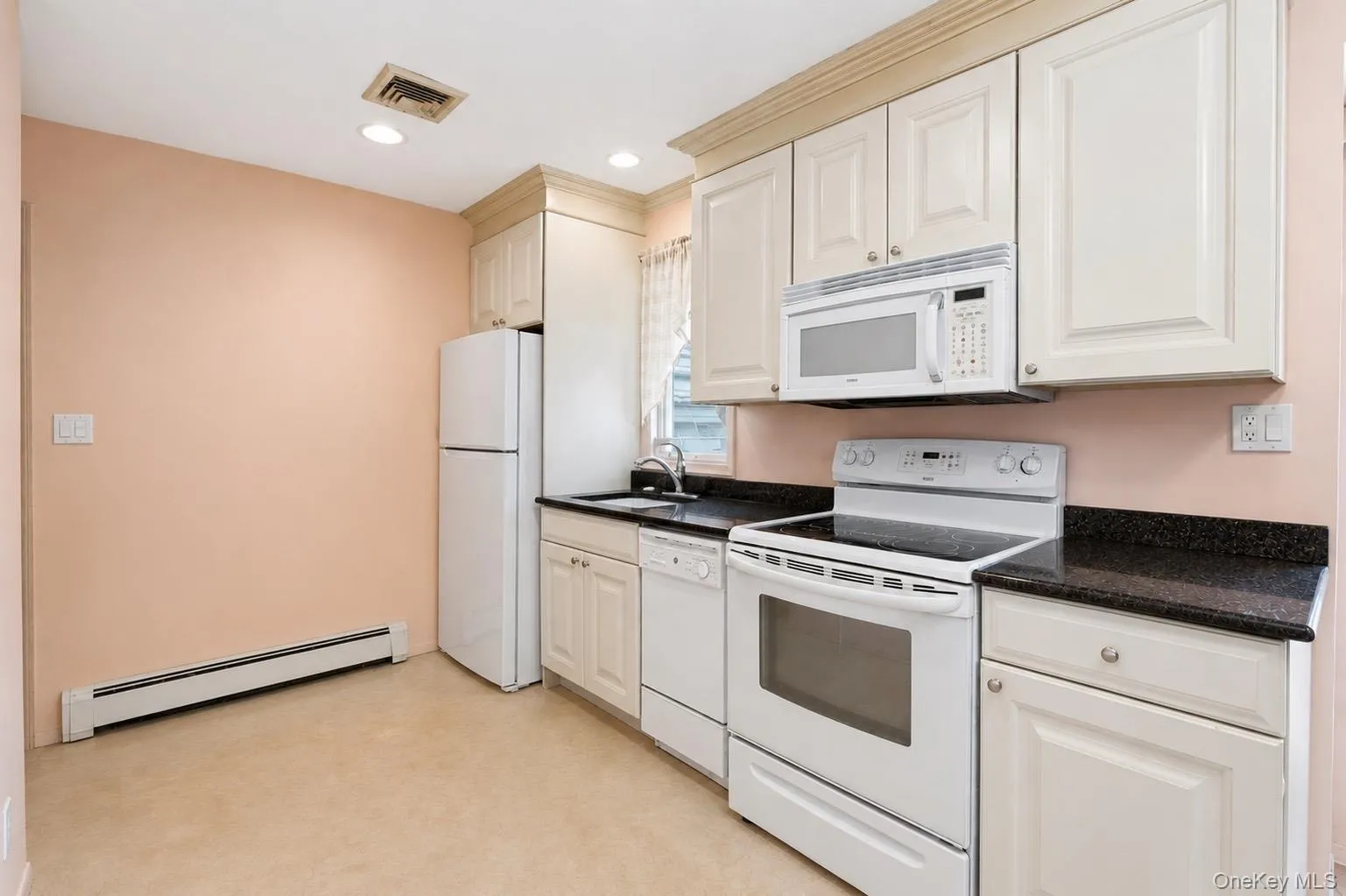 Kitchen featuring white cabinetry, black stone countertops, and integrated white appliances Kitchen featuring white cabinetry, black stone countertops, and integrated white appliances