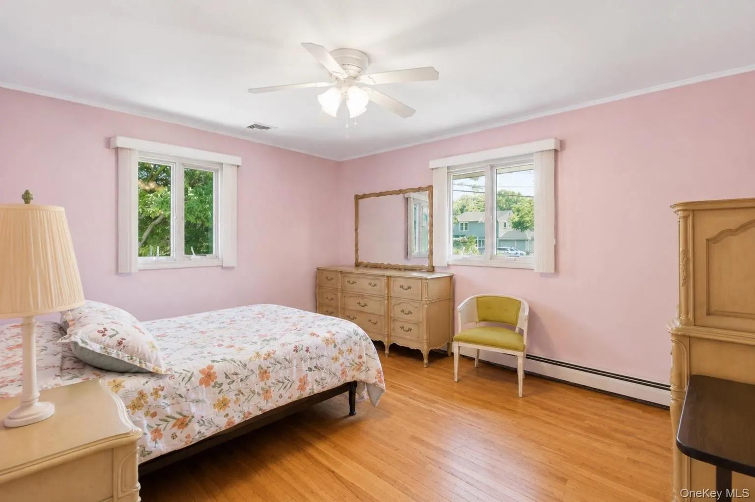 Hardwood flooring throughout featuring white baseboards, two windows with white trim, and a ceiling fan with integrated lighting Hardwood flooring throughout featuring white baseboards, two windows with white trim, and a ceiling fan with integrated lighting