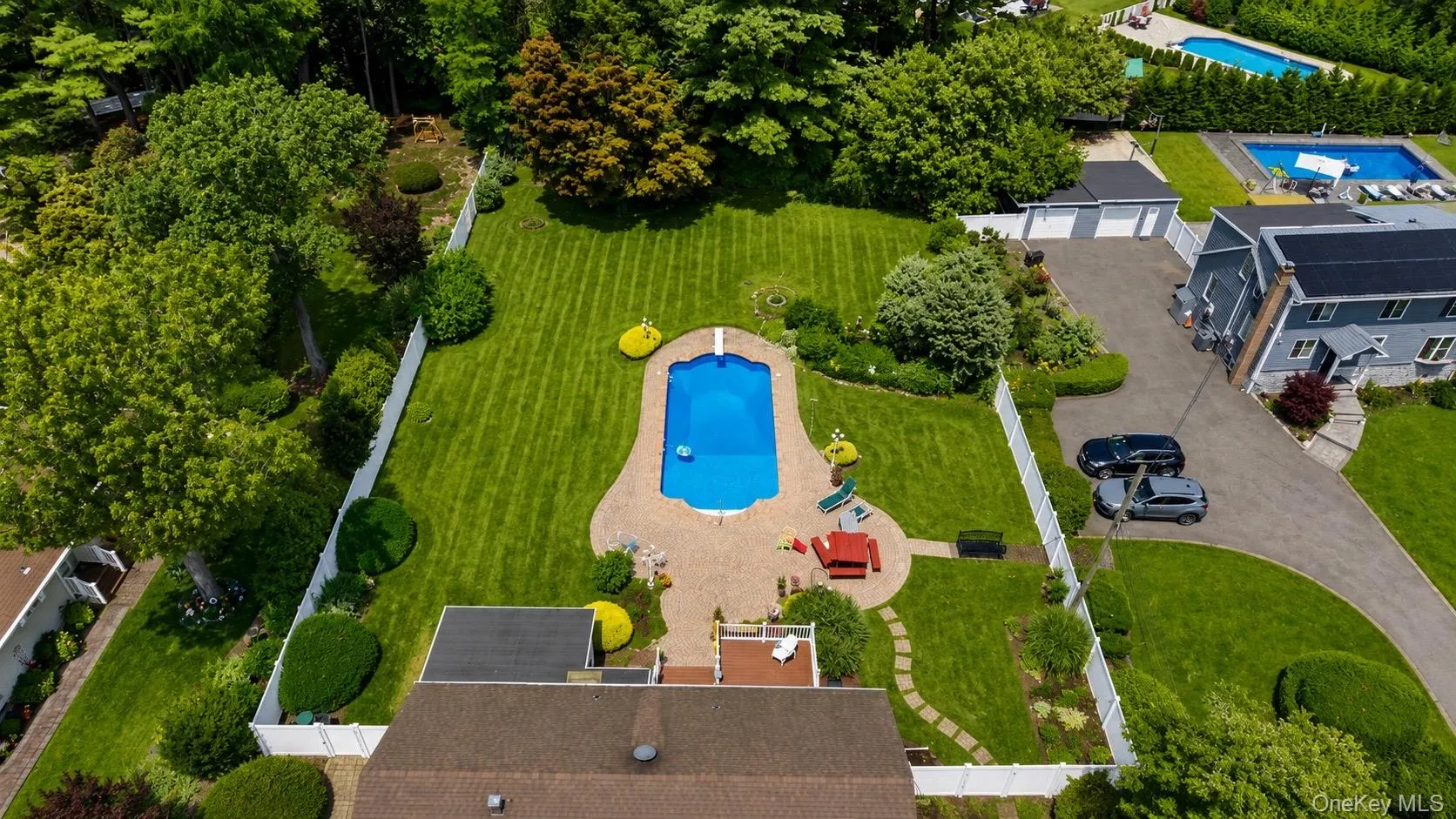 Expansive backyard featuring a large in-ground swimming pool with an integrated diving board, surrounded by paver patio areas Expansive backyard featuring a large in-ground swimming pool with an integrated diving board, surrounded by paver patio areas