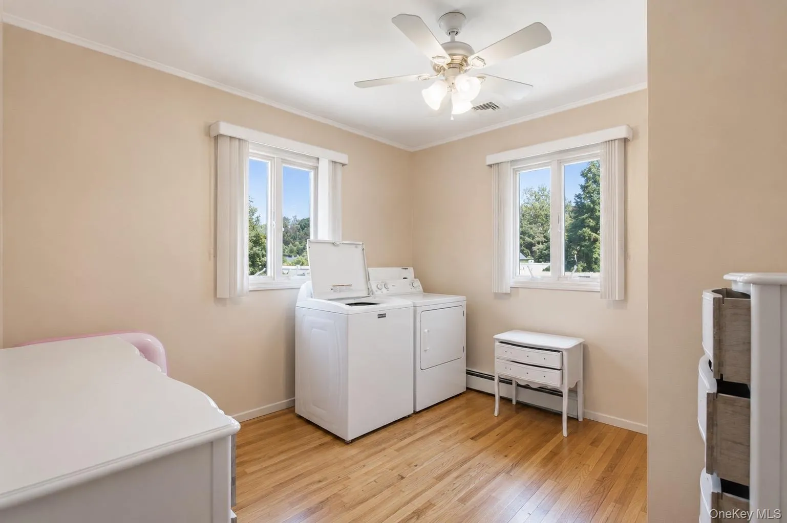 Room featuring wood-finish flooring, two windows, and a ceiling fan with integrated lighting Room featuring wood-finish flooring, two windows, and a ceiling fan with integrated lighting
