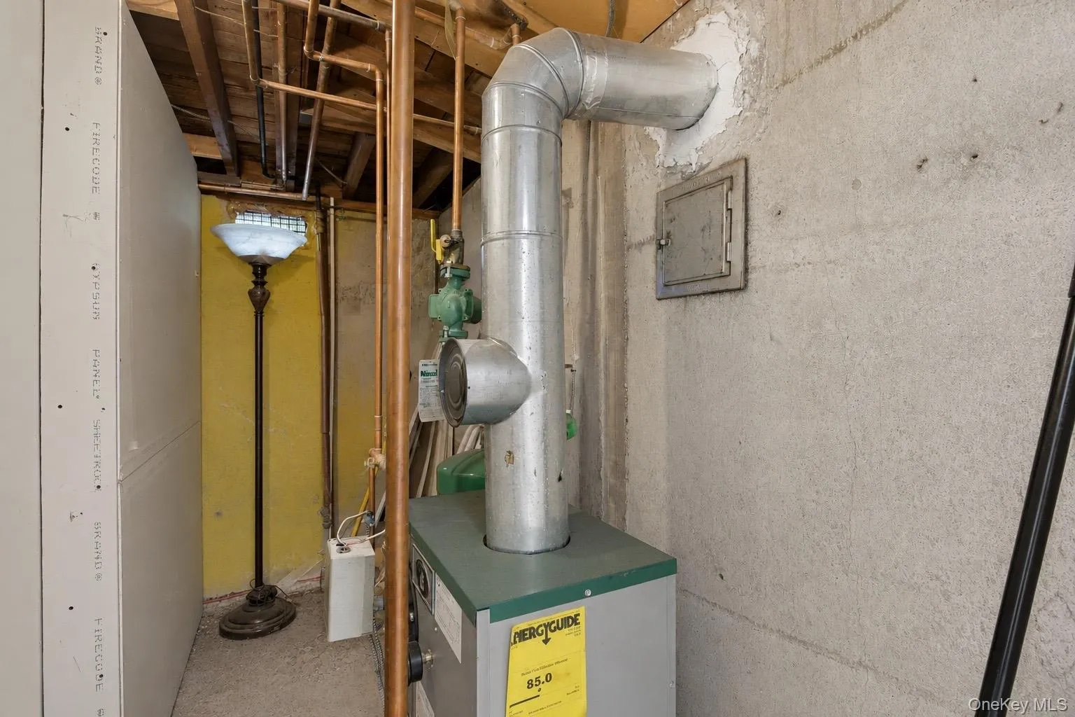 Basement utility area featuring a furnace, exposed copper piping, and concrete walls Basement utility area featuring a furnace, exposed copper piping, and concrete walls