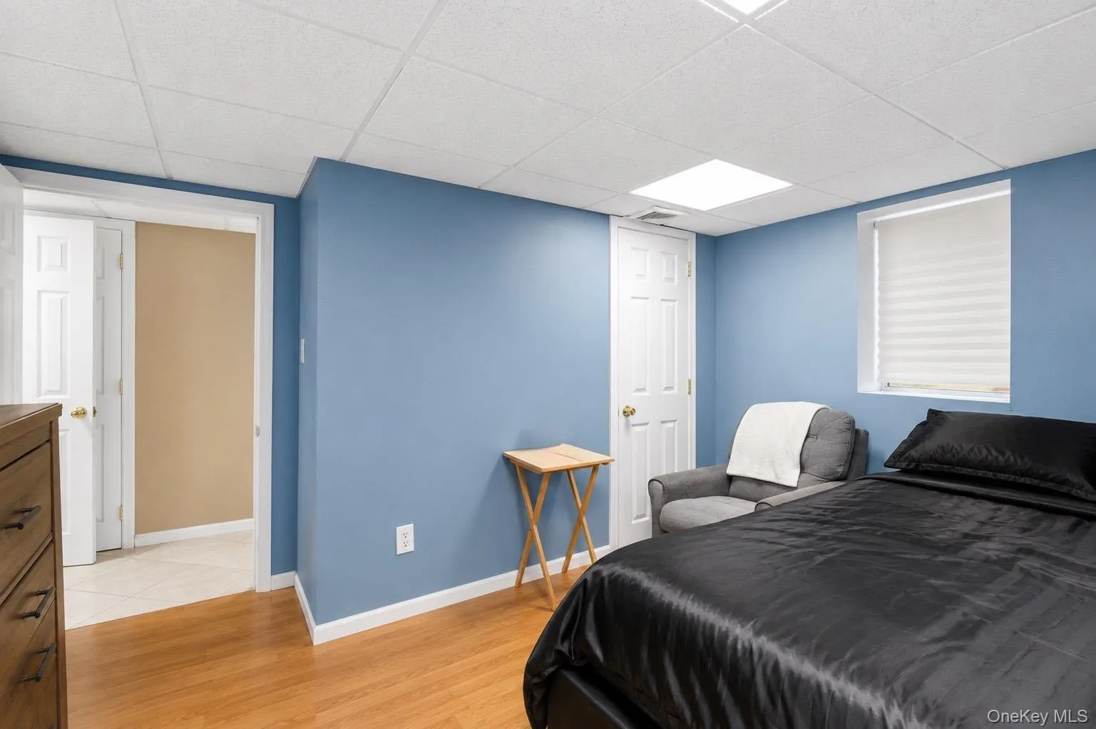 Room featuring light blue walls, wood-finish flooring, and a white acoustical tile ceiling Room featuring light blue walls, wood-finish flooring, and a white acoustical tile ceiling