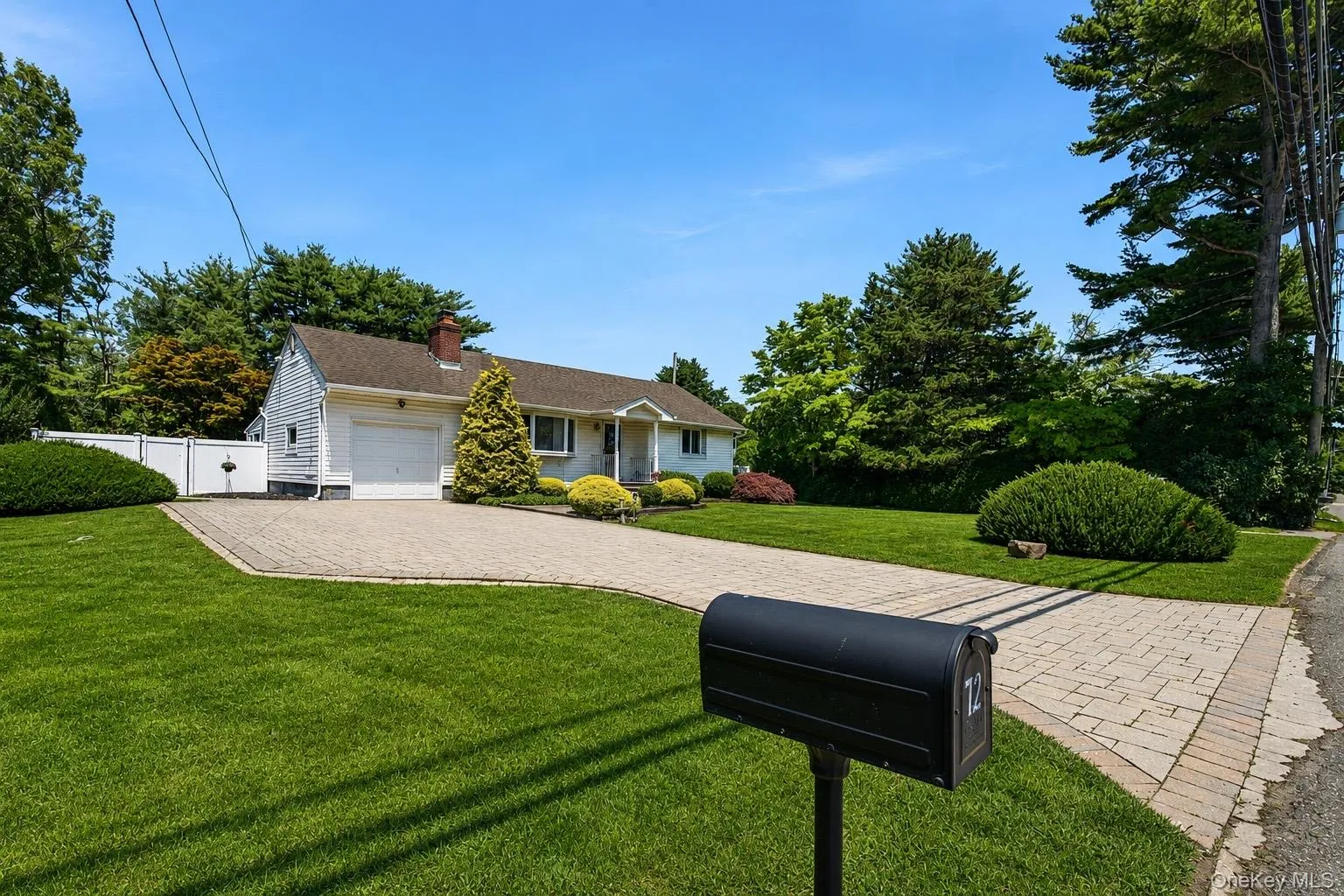 Cottage-style residence featuring a white exterior, attached single-car garage, and a paver driveway Cottage-style residence featuring a white exterior, attached single-car garage, and a paver driveway