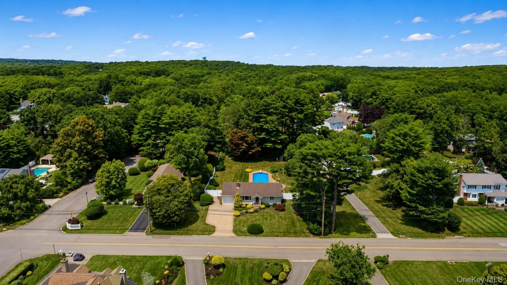 Expansive suburban property featuring a single-story residence with an attached garage, a paved driveway, and a private backyard pool Expansive suburban property featuring a single-story residence with an attached garage, a paved driveway, and a private backyard pool