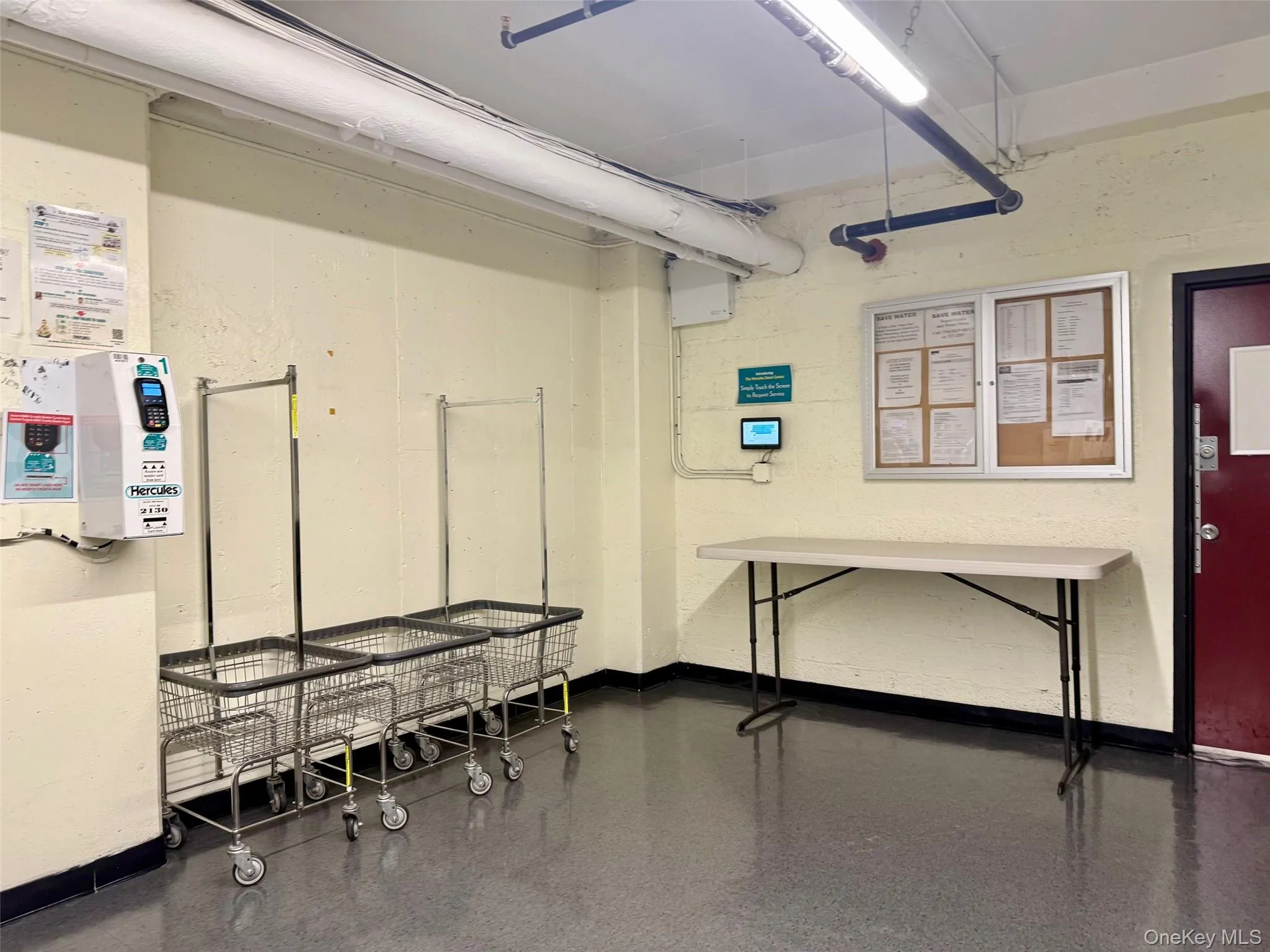 Community laundry room featuring multiple front-loading washing machines, durable flooring, and overhead fluorescent lighting Community laundry room featuring multiple front-loading washing machines, durable flooring, and overhead fluorescent lighting