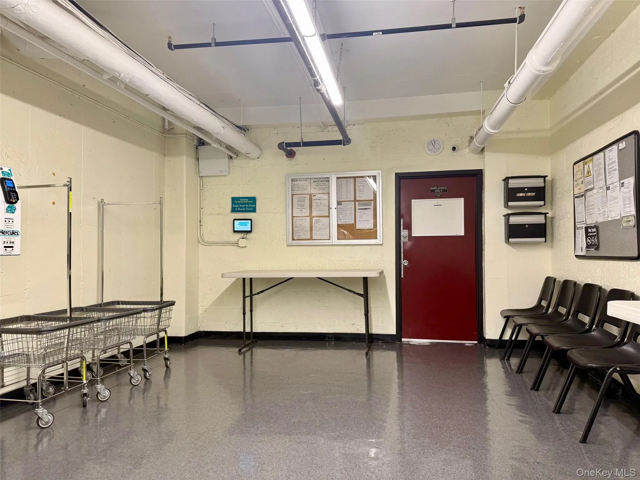 Community laundry room featuring multiple front-loading washing machines, durable flooring, and overhead fluorescent lighting Community laundry room featuring multiple front-loading washing machines, durable flooring, and overhead fluorescent lighting