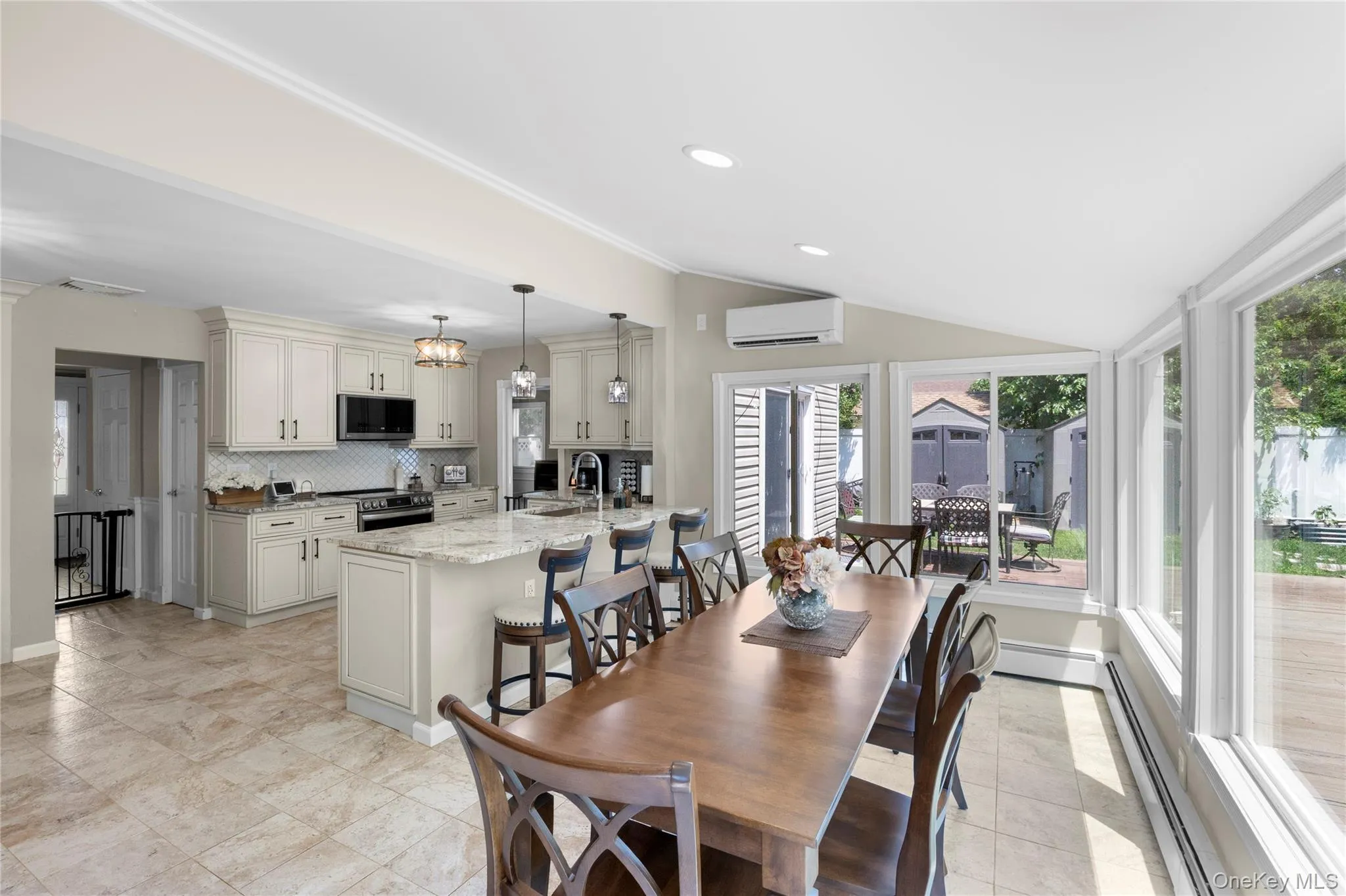 Open-concept kitchen and dining area featuring light-toned cabinetry, granite countertops, and tile flooring Open-concept kitchen and dining area featuring light-toned cabinetry, granite countertops, and tile flooring