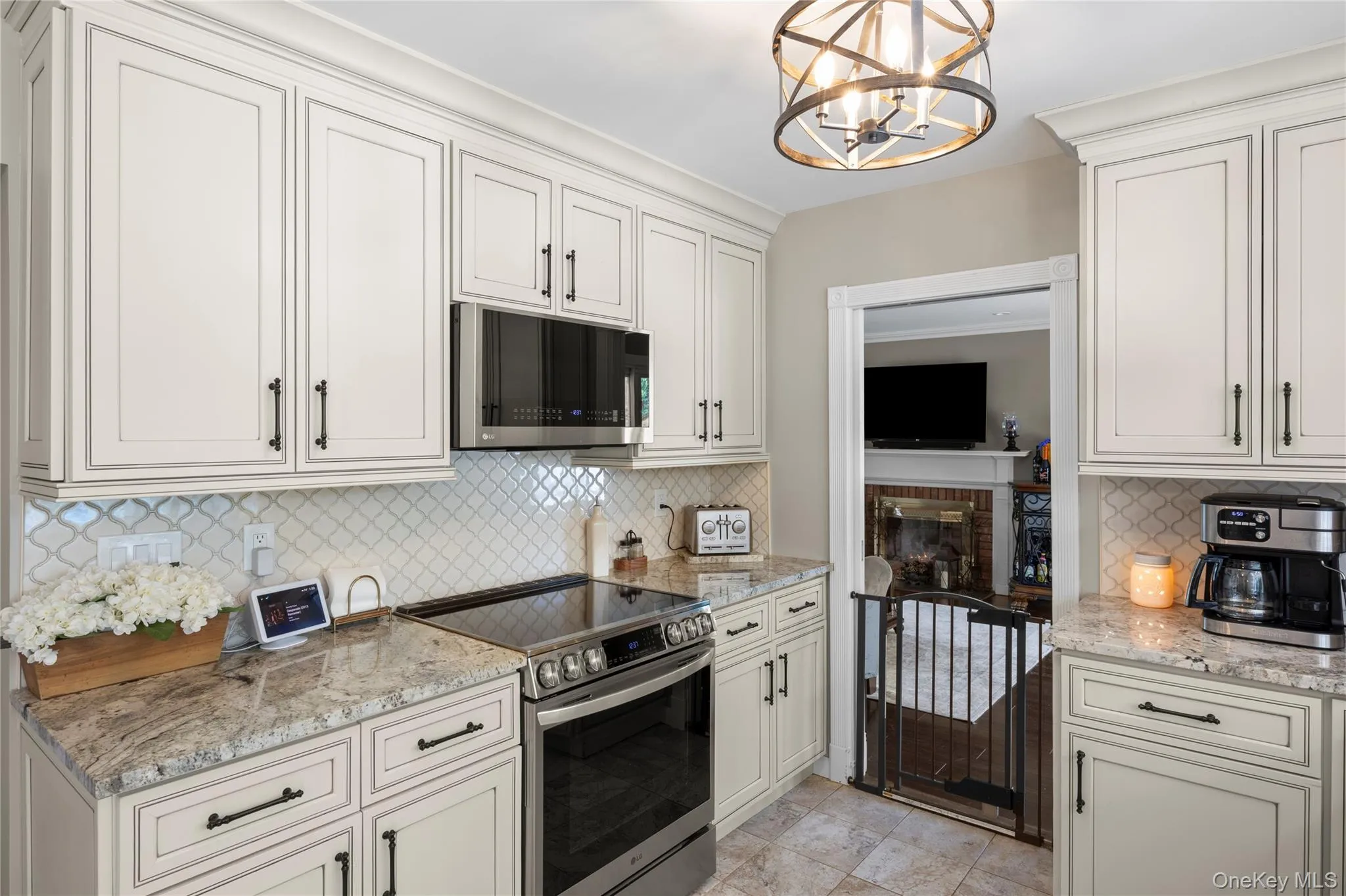 Kitchen featuring light-toned cabinetry with dark hardware, granite countertops, and a decorative tile backsplash Kitchen featuring light-toned cabinetry with dark hardware, granite countertops, and a decorative tile backsplash