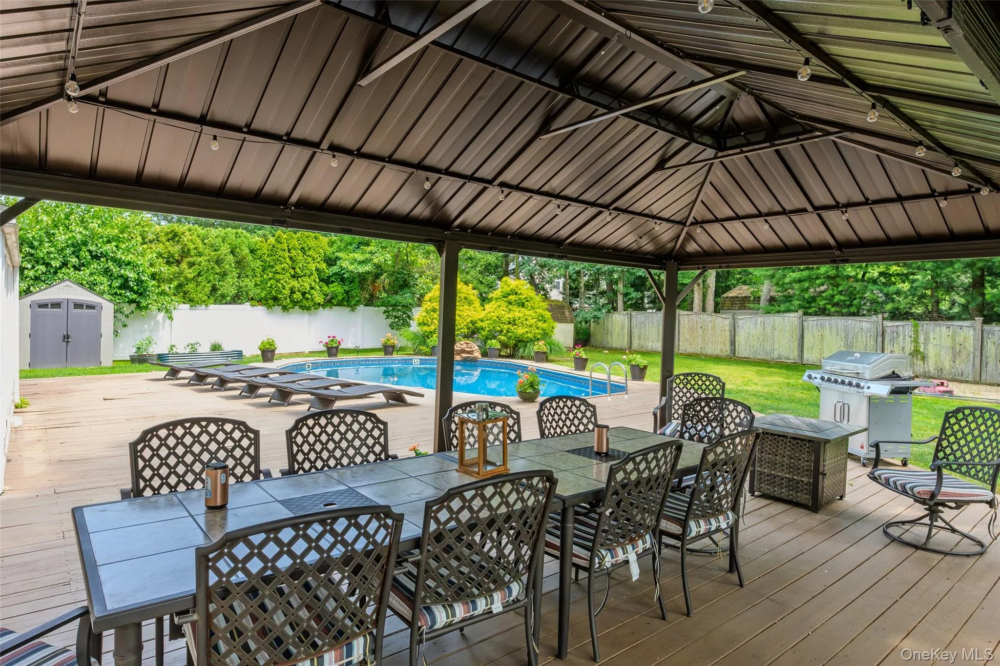Expansive outdoor living area featuring a covered gazebo over a dining space, a swimming pool, and a dedicated pool deck Expansive outdoor living area featuring a covered gazebo over a dining space, a swimming pool, and a dedicated pool deck