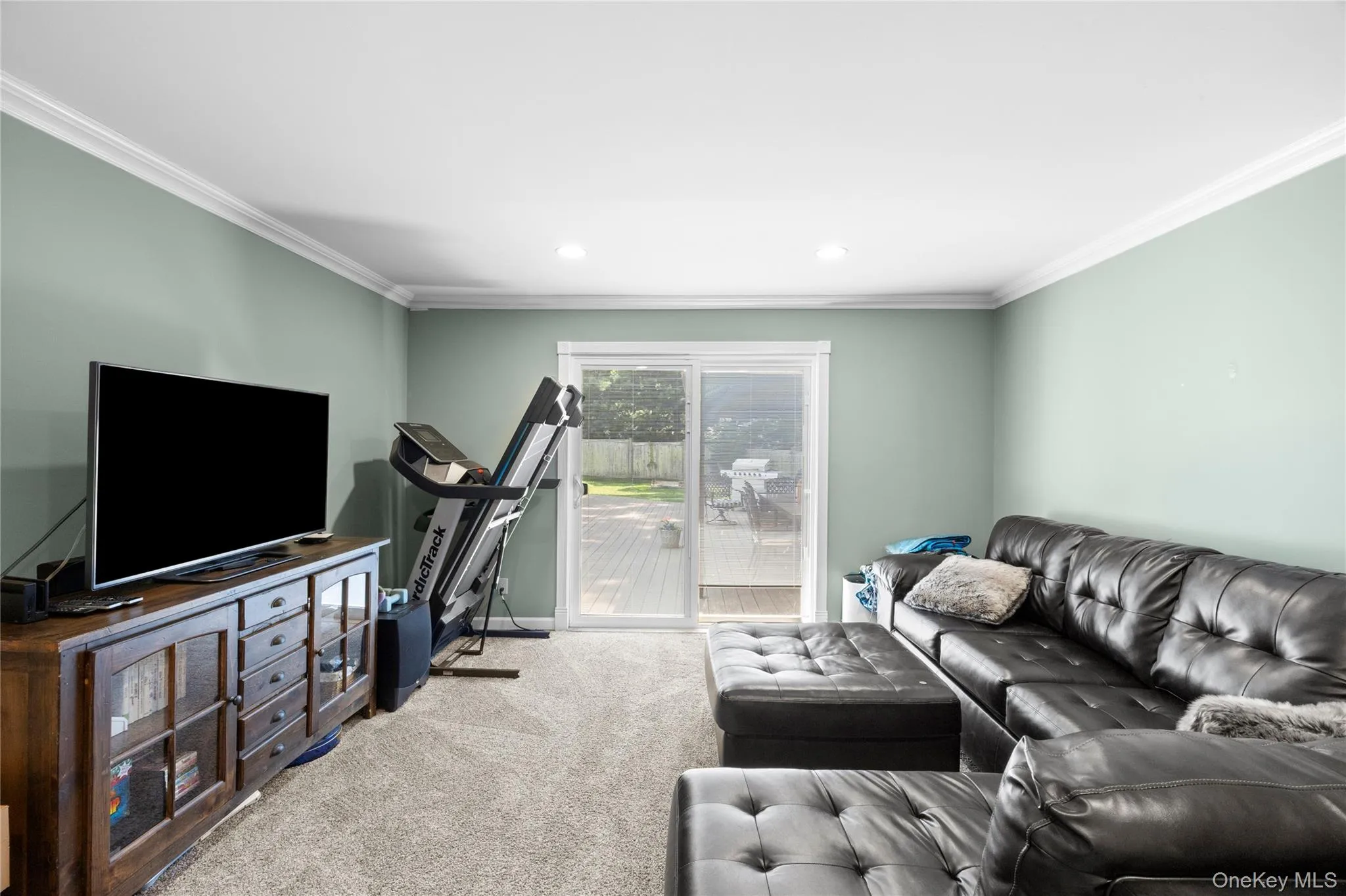 Carpeted living area featuring light green walls, white crown molding, and recessed lighting Carpeted living area featuring light green walls, white crown molding, and recessed lighting