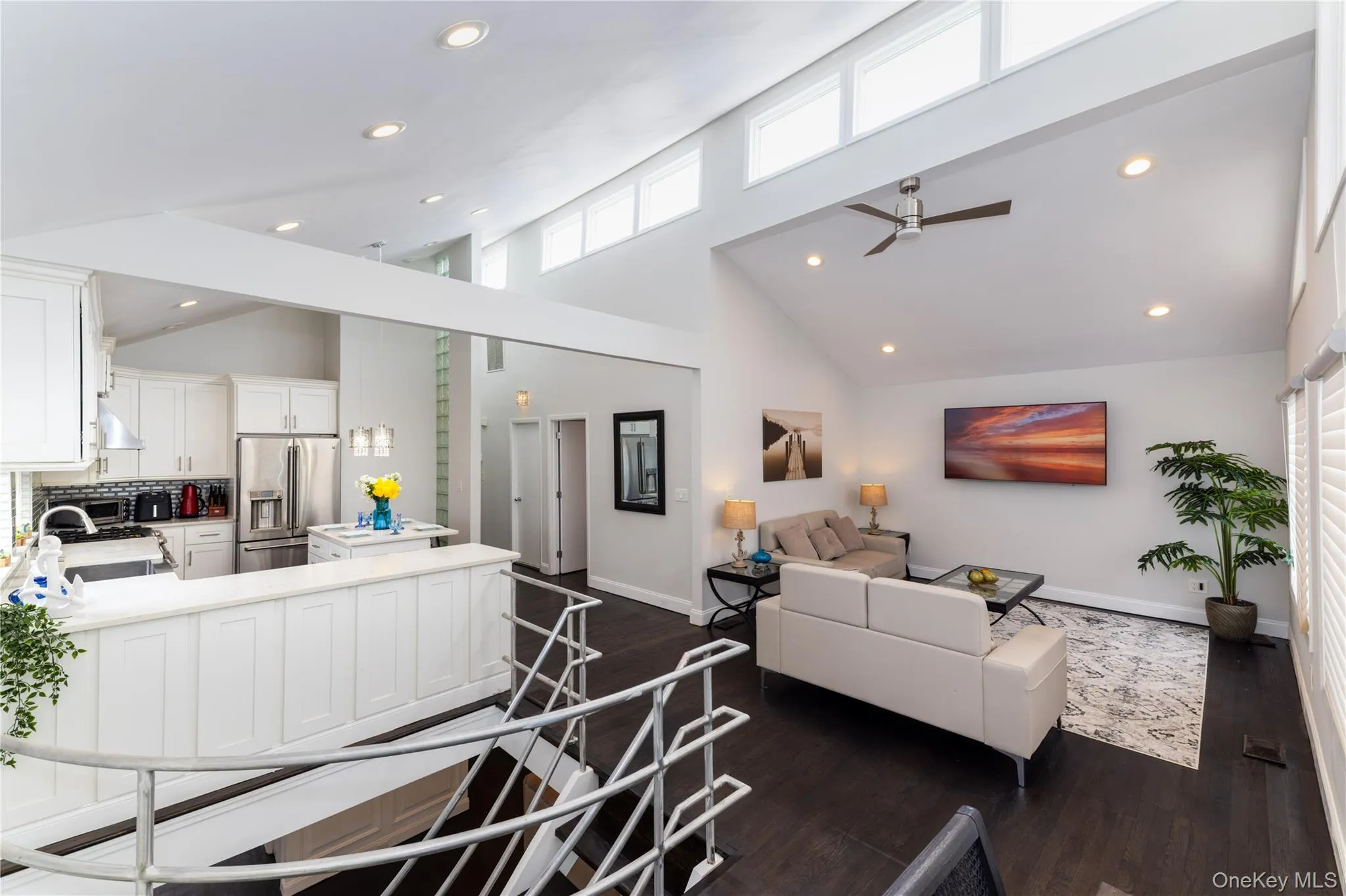 Expansive open-concept living area featuring a vaulted ceiling and dark wood-finish flooring Expansive open-concept living area featuring a vaulted ceiling and dark wood-finish flooring