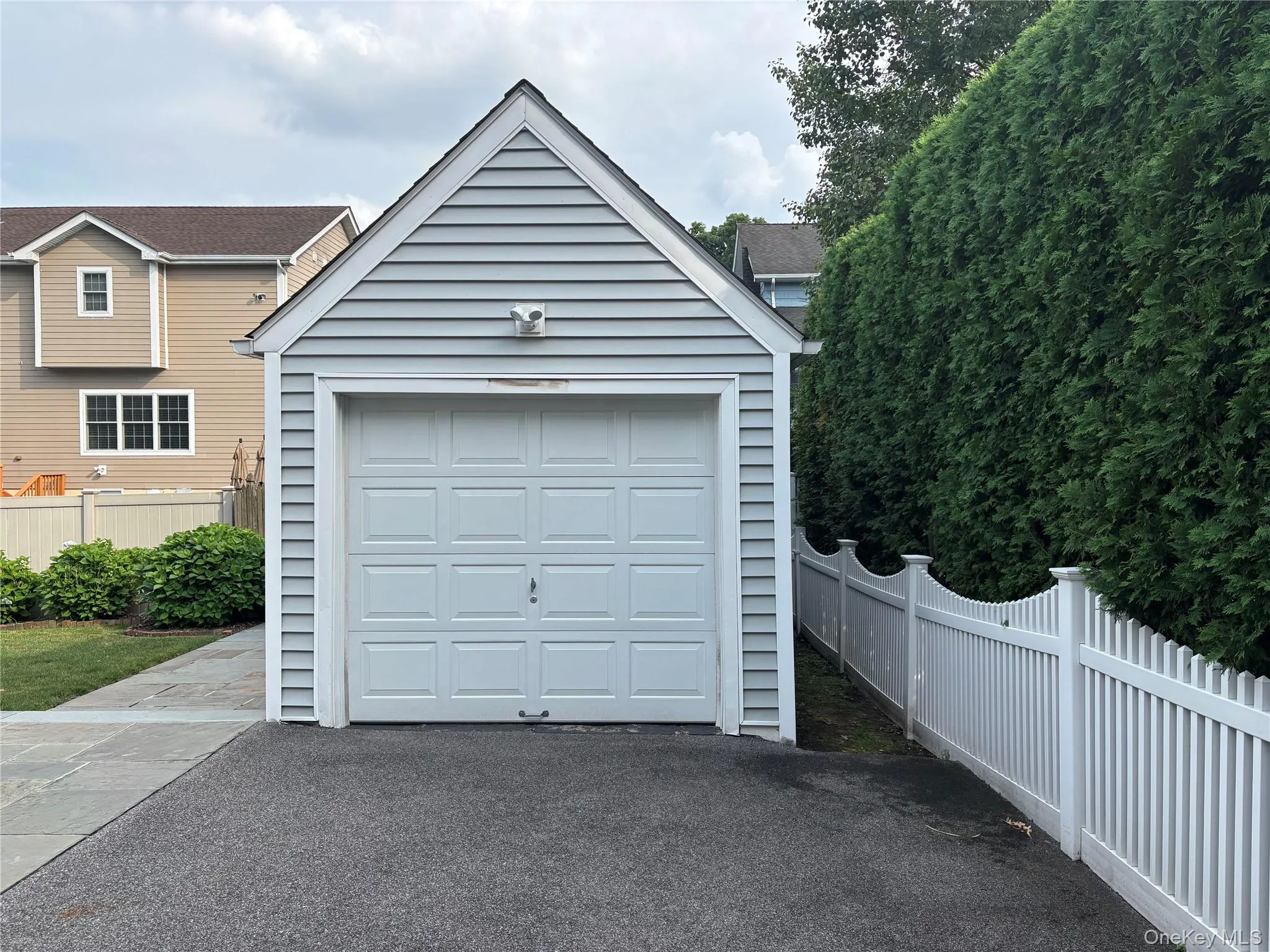 Detached garage featuring light gray siding and a white panel garage door Detached garage featuring light gray siding and a white panel garage door