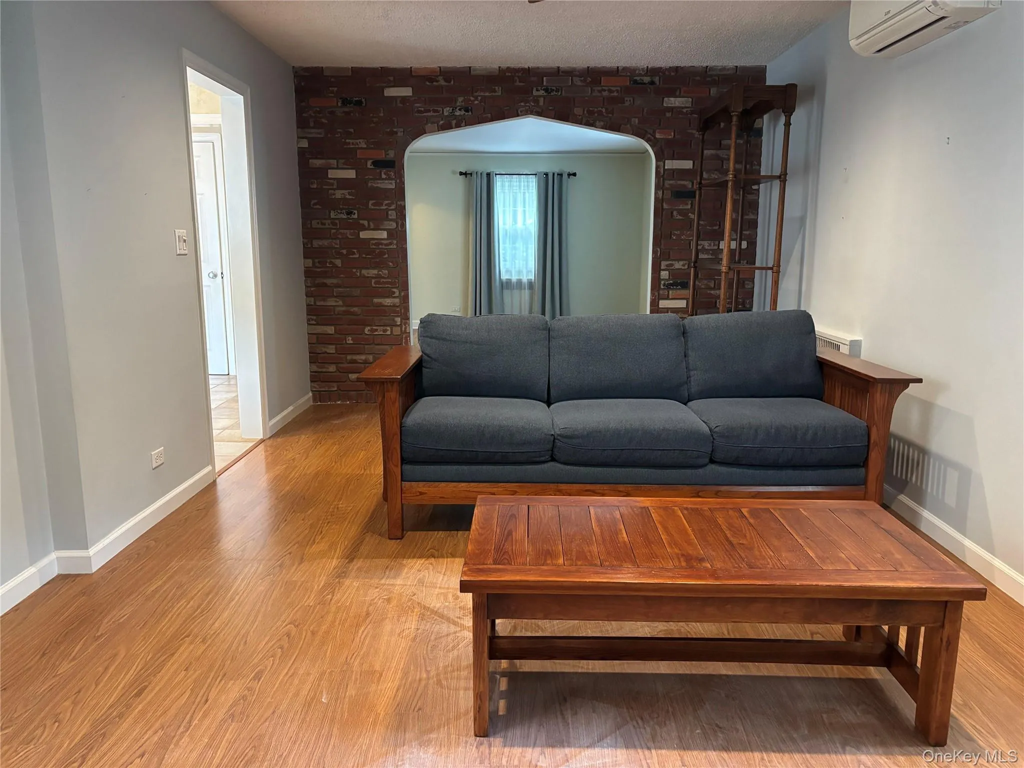 Wood-finish flooring throughout, complemented by a brick-accented arched doorway Wood-finish flooring throughout, complemented by a brick-accented arched doorway