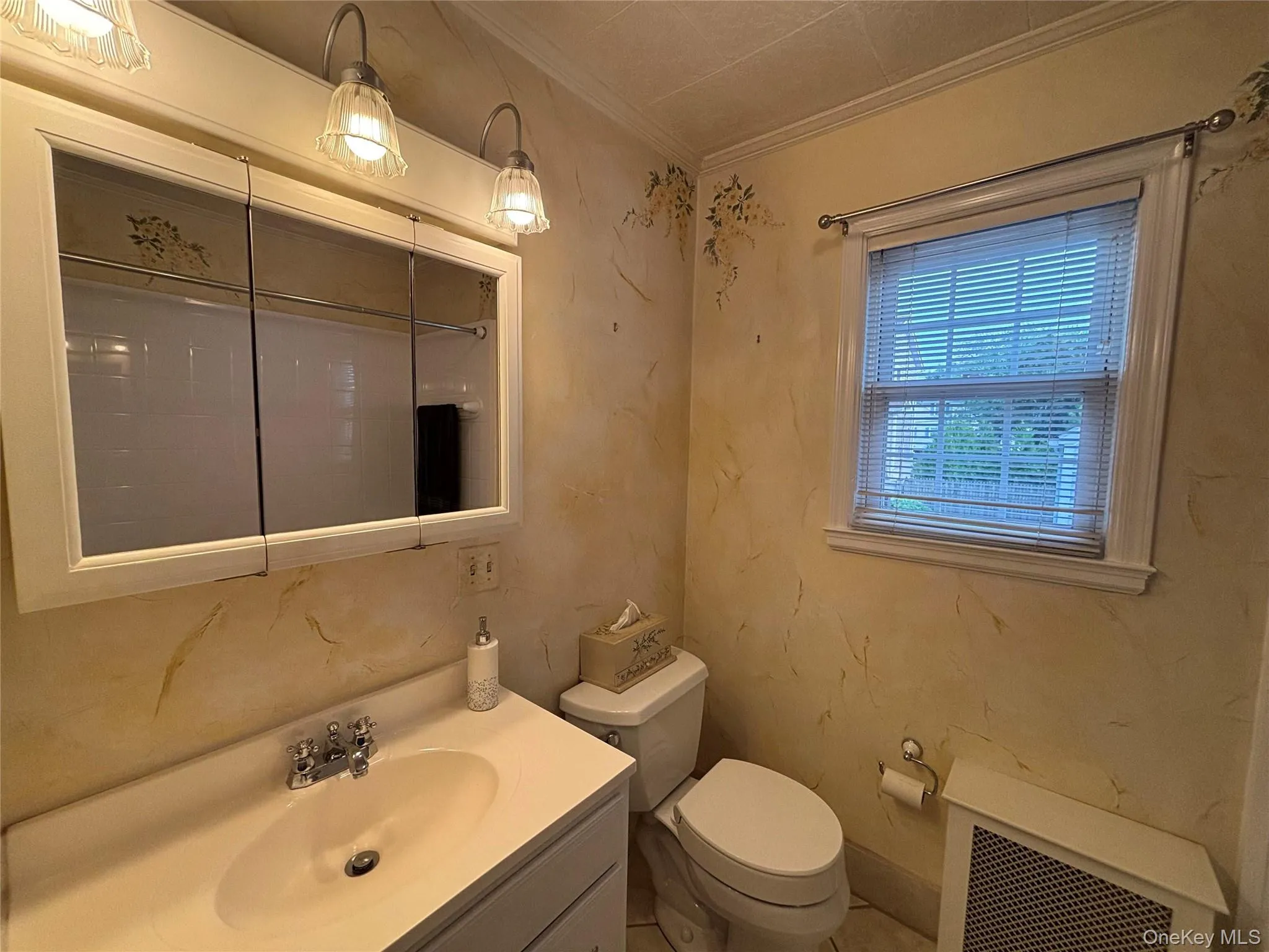 Bathroom featuring a white vanity with integrated sink, chrome faucet, and a wall-mounted medicine cabinet with integrated lighting Bathroom featuring a white vanity with integrated sink, chrome faucet, and a wall-mounted medicine cabinet with integrated lighting