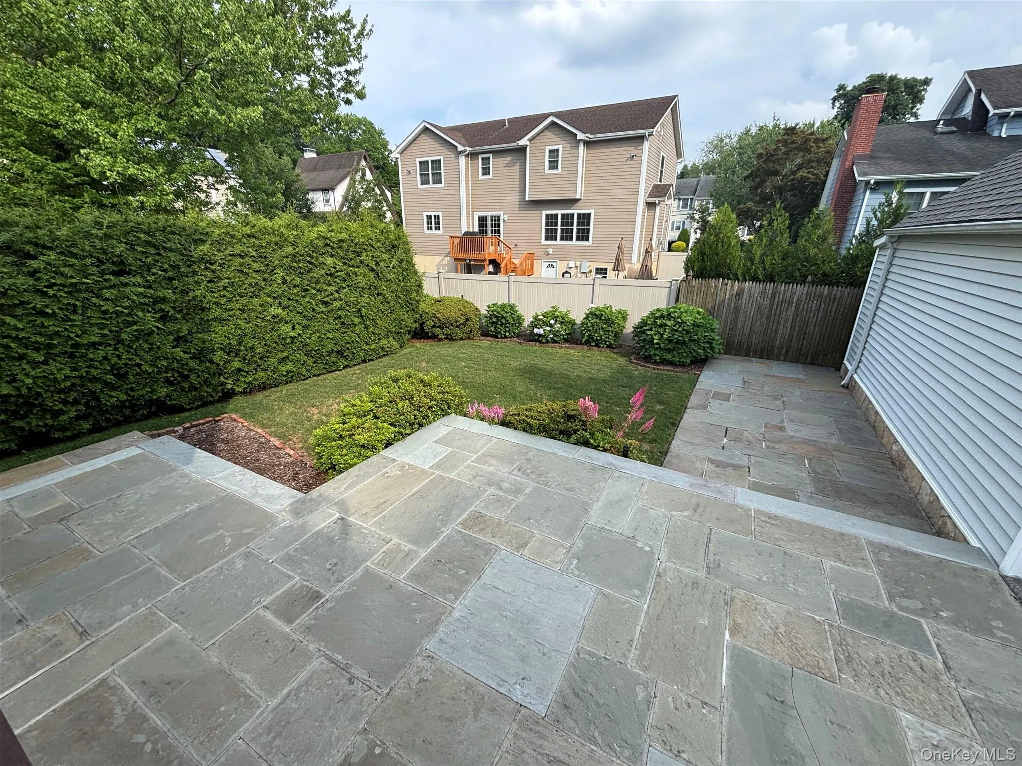 Multi-level stone patio extending to a manicured lawn area Multi-level stone patio extending to a manicured lawn area