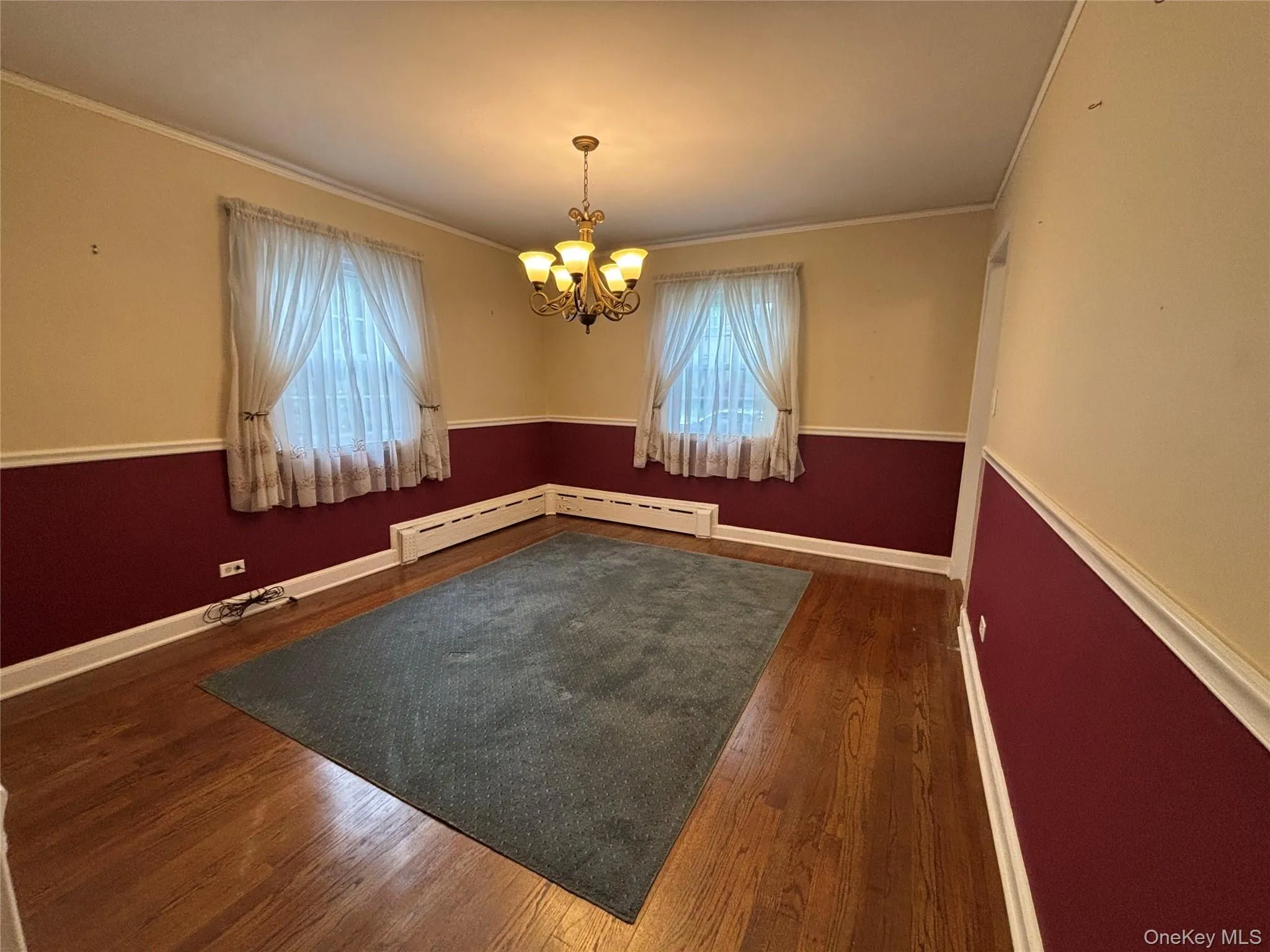 Interior room featuring wood-finish flooring, a decorative chandelier, and a window with sheer curtains Interior room featuring wood-finish flooring, a decorative chandelier, and a window with sheer curtains