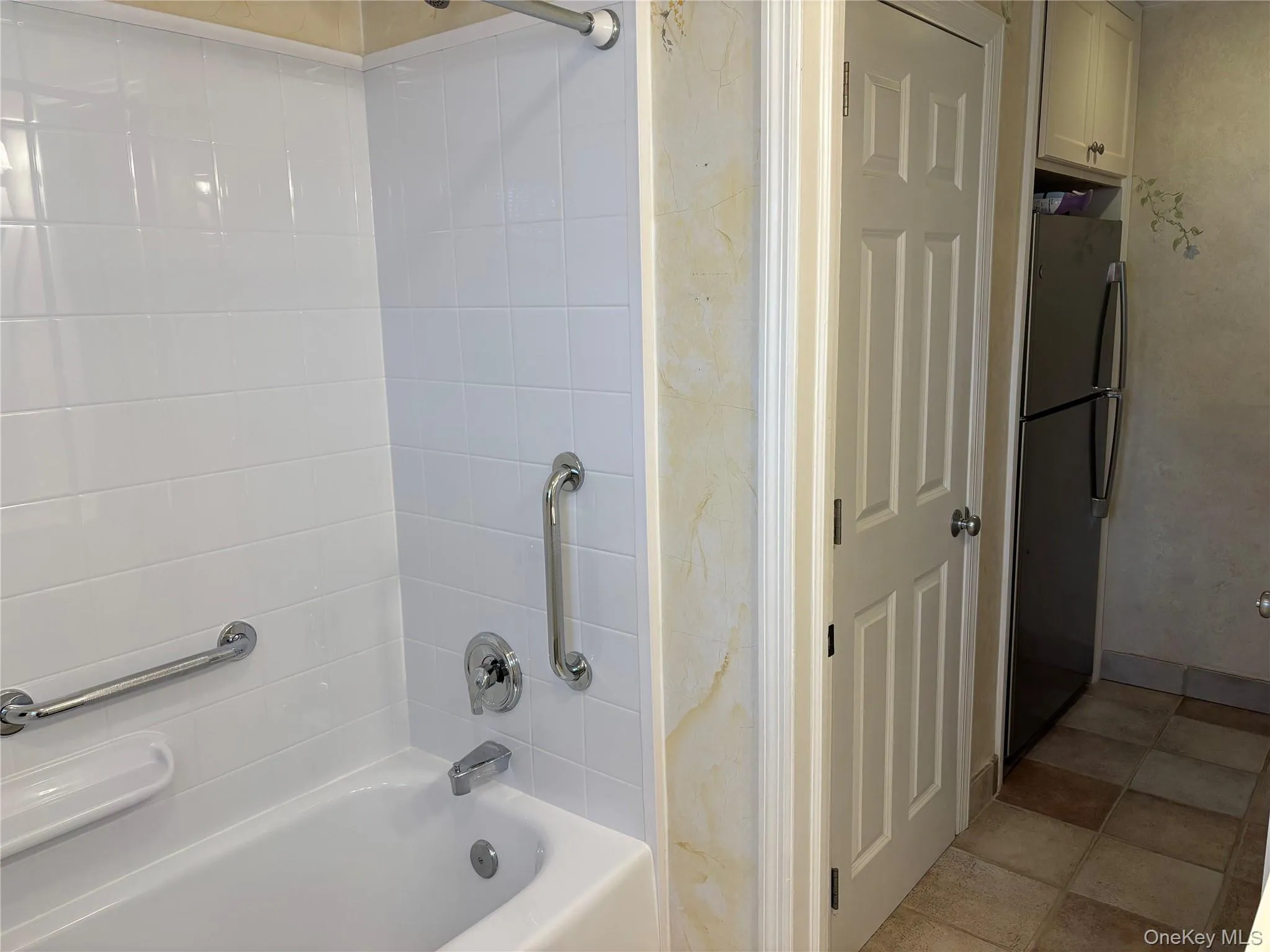 Bathtub with white subway tile surround, chrome fixtures, and integrated grab bars Bathtub with white subway tile surround, chrome fixtures, and integrated grab bars