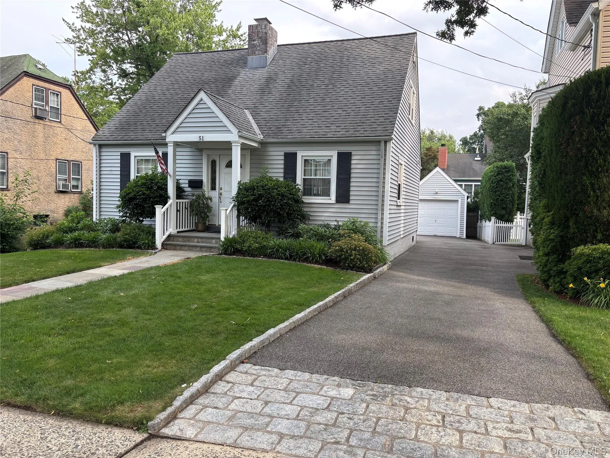 Gabled home with light grey siding, a covered front entry, and black window shutters Gabled home with light grey siding, a covered front entry, and black window shutters