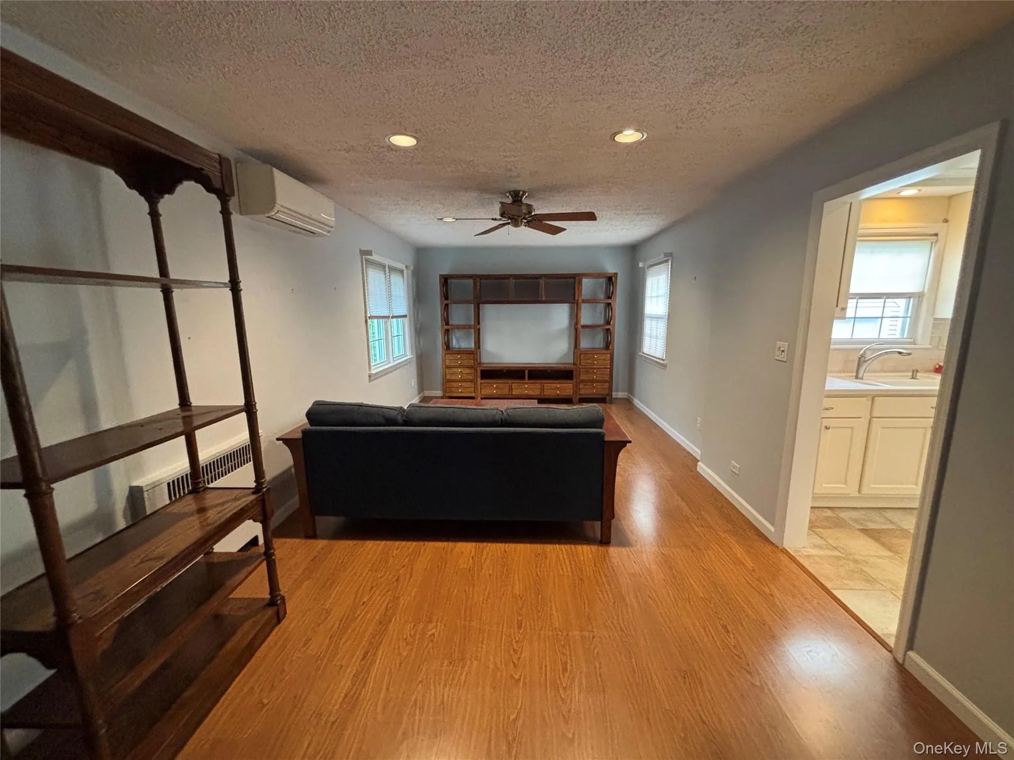 Spacious living area featuring wood-finish flooring, recessed lighting, and a ceiling fan Spacious living area featuring wood-finish flooring, recessed lighting, and a ceiling fan