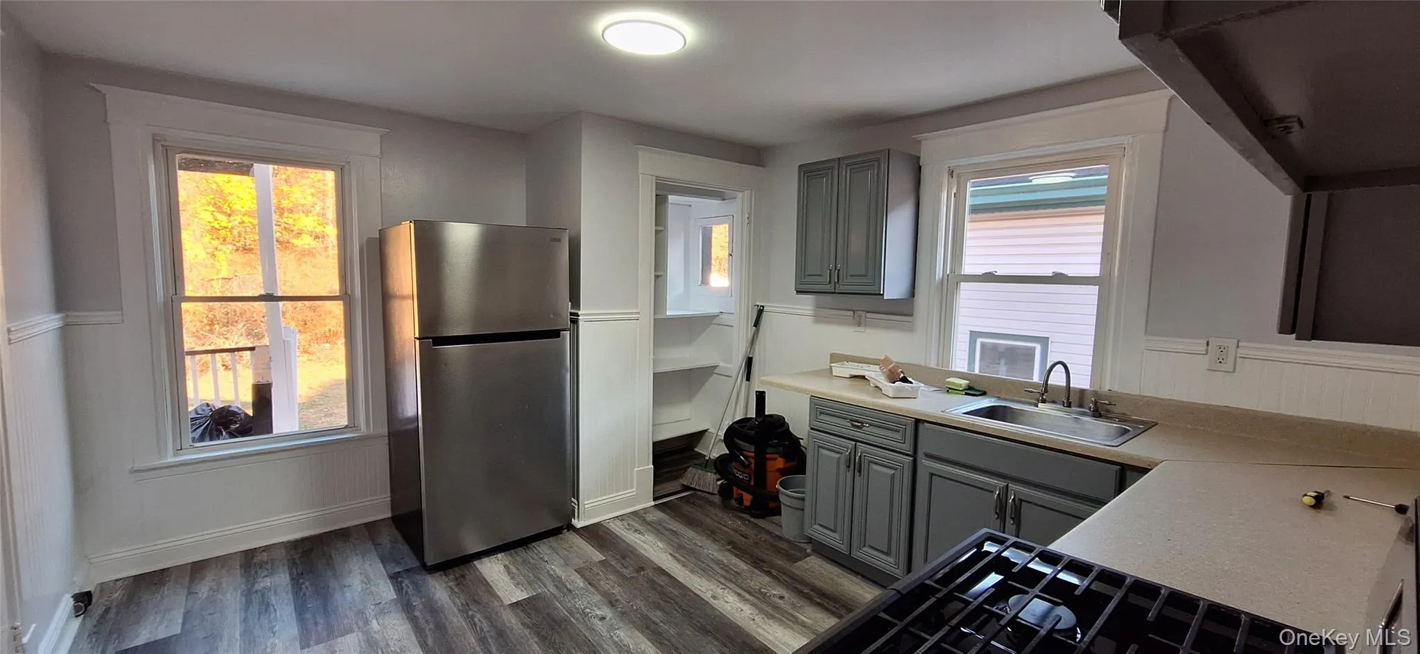 Kitchen featuring stainless steel fridge, floors, gray cabinetry, and sink Kitchen featuring stainless steel fridge, floors, gray cabinetry, and sink