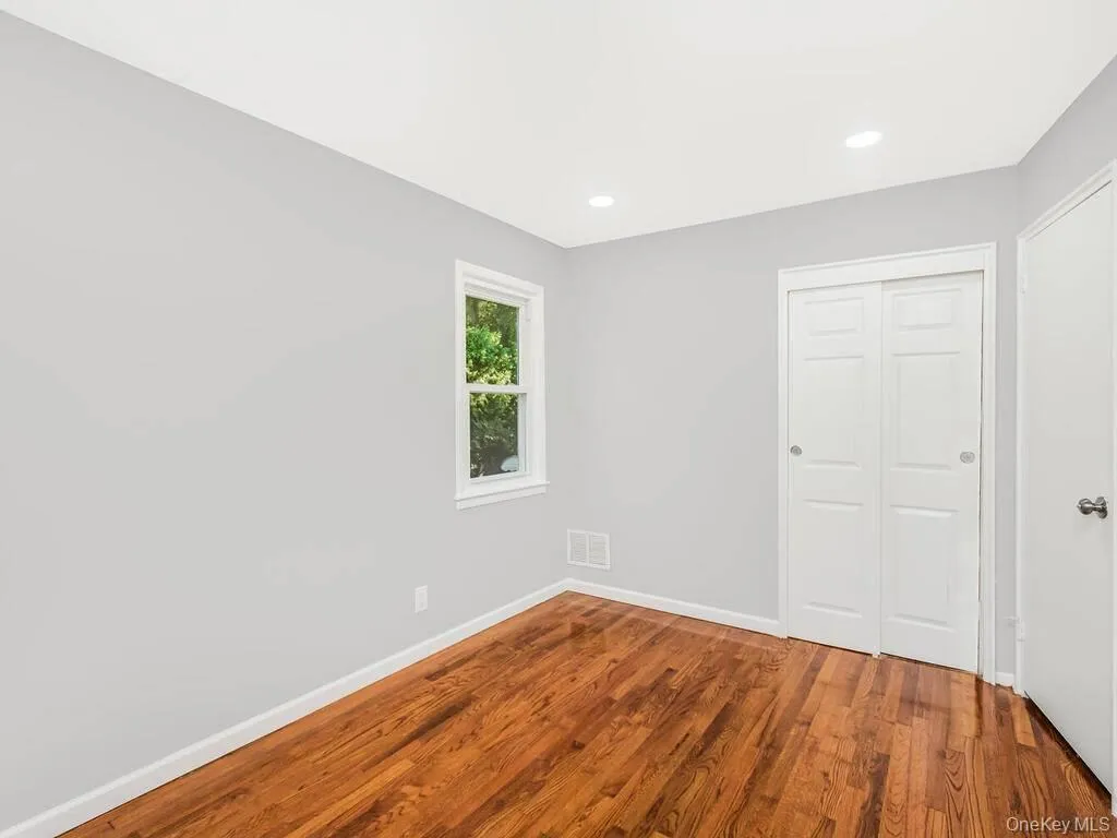Hardwood flooring, recessed lighting, double bi-fold closet doors, white trim, and a window with natural light Hardwood flooring, recessed lighting, double bi-fold closet doors, white trim, and a window with natural light