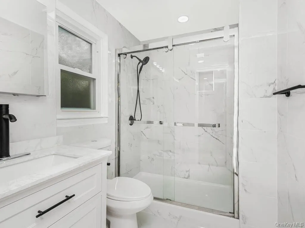 Bathroom featuring a white vanity with an integrated sink, quartz countertop, and matte black faucet Bathroom featuring a white vanity with an integrated sink, quartz countertop, and matte black faucet