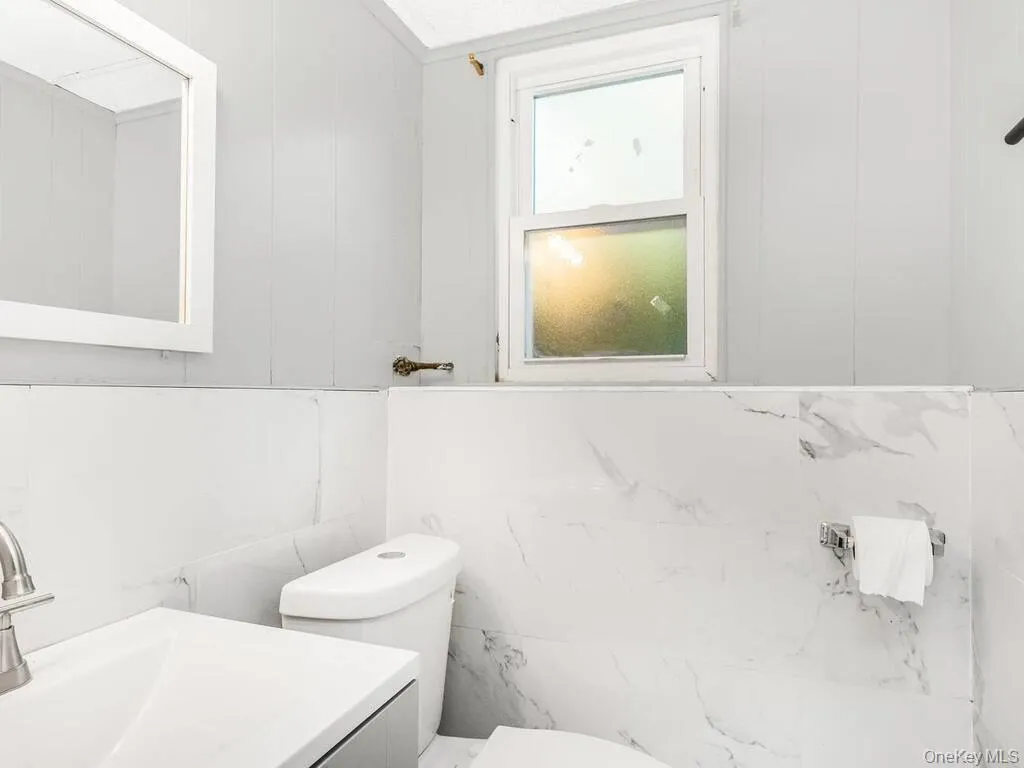 Bathroom featuring a white vanity with an integrated sink, brushed nickel faucet, and a wall-mounted mirror Bathroom featuring a white vanity with an integrated sink, brushed nickel faucet, and a wall-mounted mirror