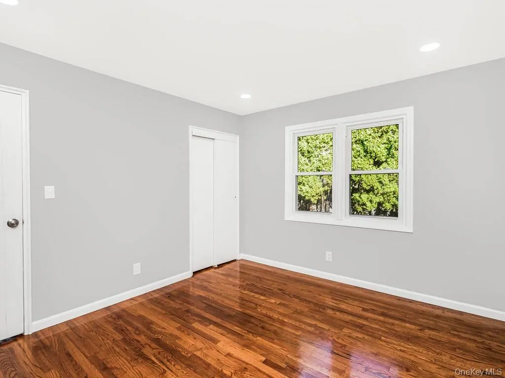 Room featuring rich wood flooring, neutral wall tones, and recessed ceiling lighting Room featuring rich wood flooring, neutral wall tones, and recessed ceiling lighting