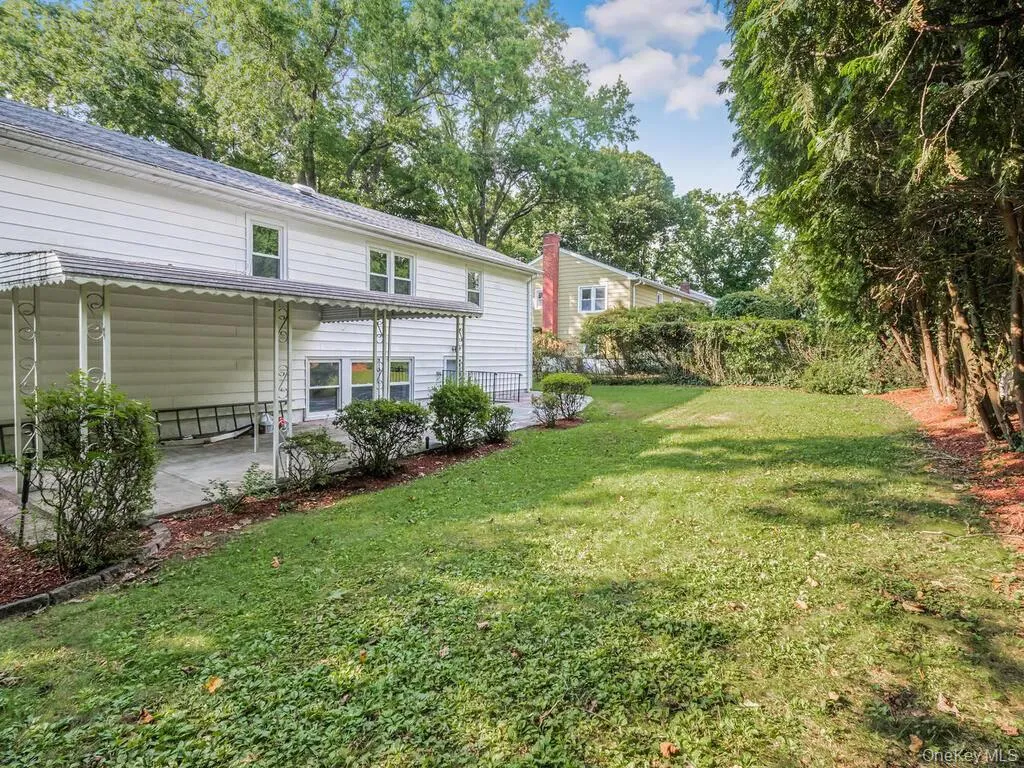 Expansive rear yard featuring a manicured lawn, established perimeter trees, and a concrete patio Expansive rear yard featuring a manicured lawn, established perimeter trees, and a concrete patio
