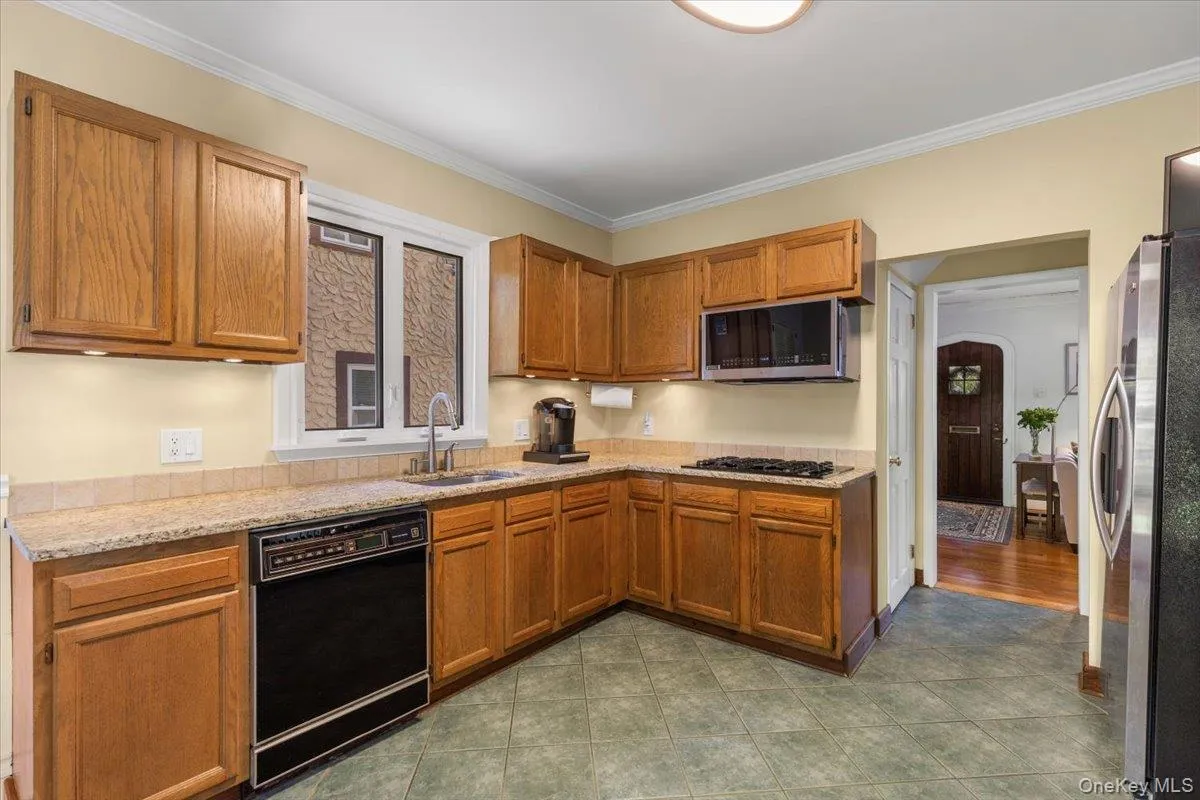 Kitchen featuring wood cabinetry, granite-finish countertops, tile flooring, built-in microwave, and a gas cooktop Kitchen featuring wood cabinetry, granite-finish countertops, tile flooring, built-in microwave, and a gas cooktop