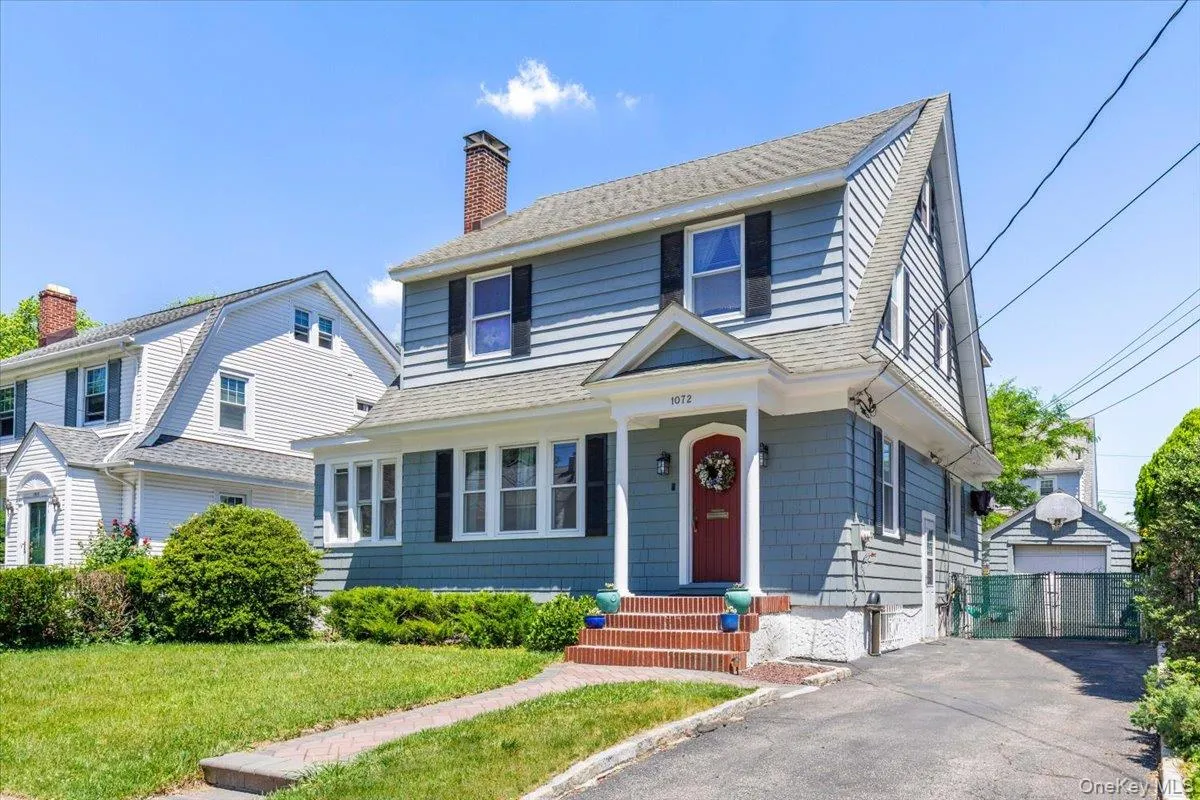 Shingle-sided exterior with a prominent red entry door and covered porch Shingle-sided exterior with a prominent red entry door and covered porch