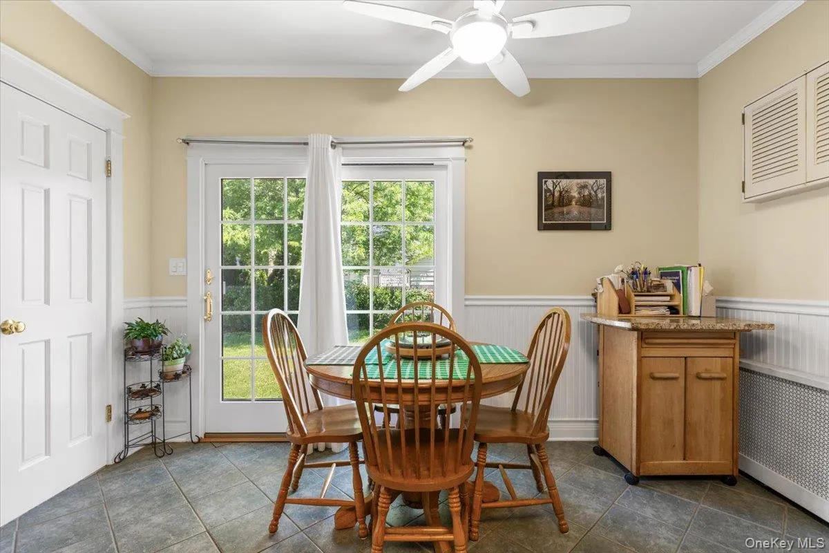 Dining area with grey tile flooring, white wainscoting, and crown molding Dining area with grey tile flooring, white wainscoting, and crown molding