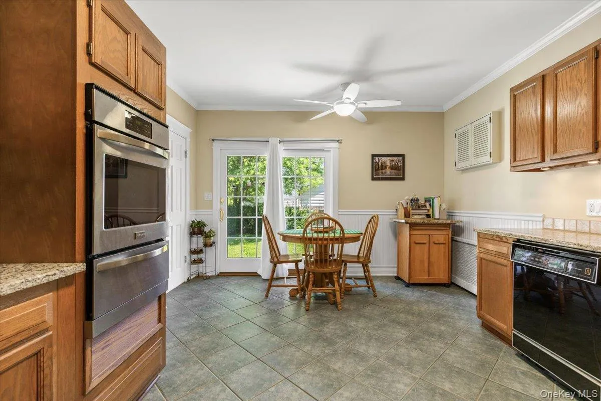 Kitchen featuring wood cabinetry, stainless steel double wall oven, tile flooring, and granite-look countertops Kitchen featuring wood cabinetry, stainless steel double wall oven, tile flooring, and granite-look countertops