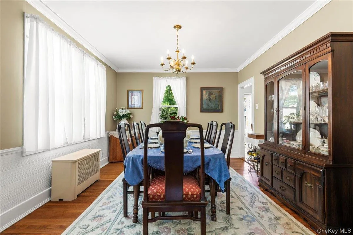 Dining room featuring warm wood-finish flooring, white wainscoting, and crown molding Dining room featuring warm wood-finish flooring, white wainscoting, and crown molding