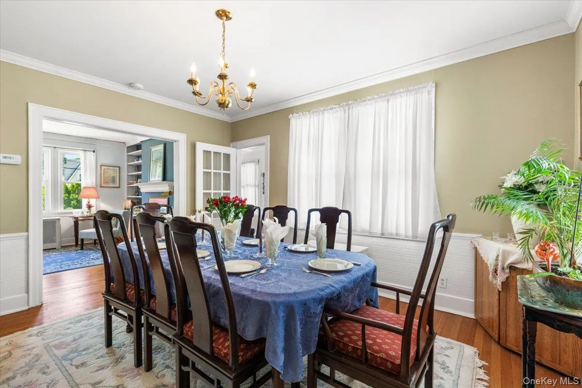 Formal dining room featuring hardwood flooring, crown molding, and wainscoting Formal dining room featuring hardwood flooring, crown molding, and wainscoting