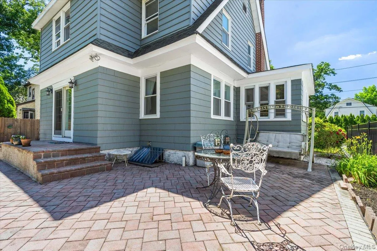 Expansive paver patio with a brick-faced raised landing and steps, featuring a sliding glass door entry to the main structure Expansive paver patio with a brick-faced raised landing and steps, featuring a sliding glass door entry to the main structure
