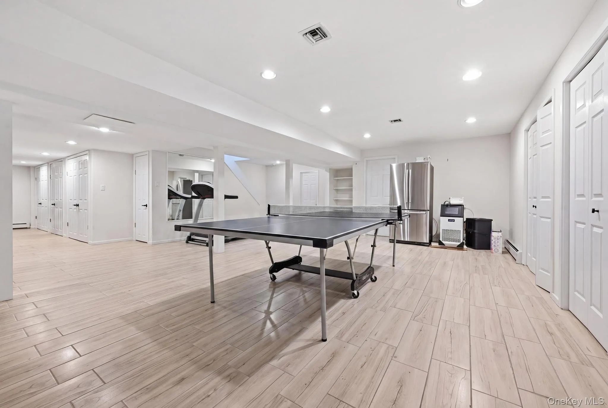 Spacious interior featuring light wood-finish flooring, recessed lighting, multiple storage closets with bifold doors, and a built-in shelving unit Spacious interior featuring light wood-finish flooring, recessed lighting, multiple storage closets with bifold doors, and a built-in shelving unit