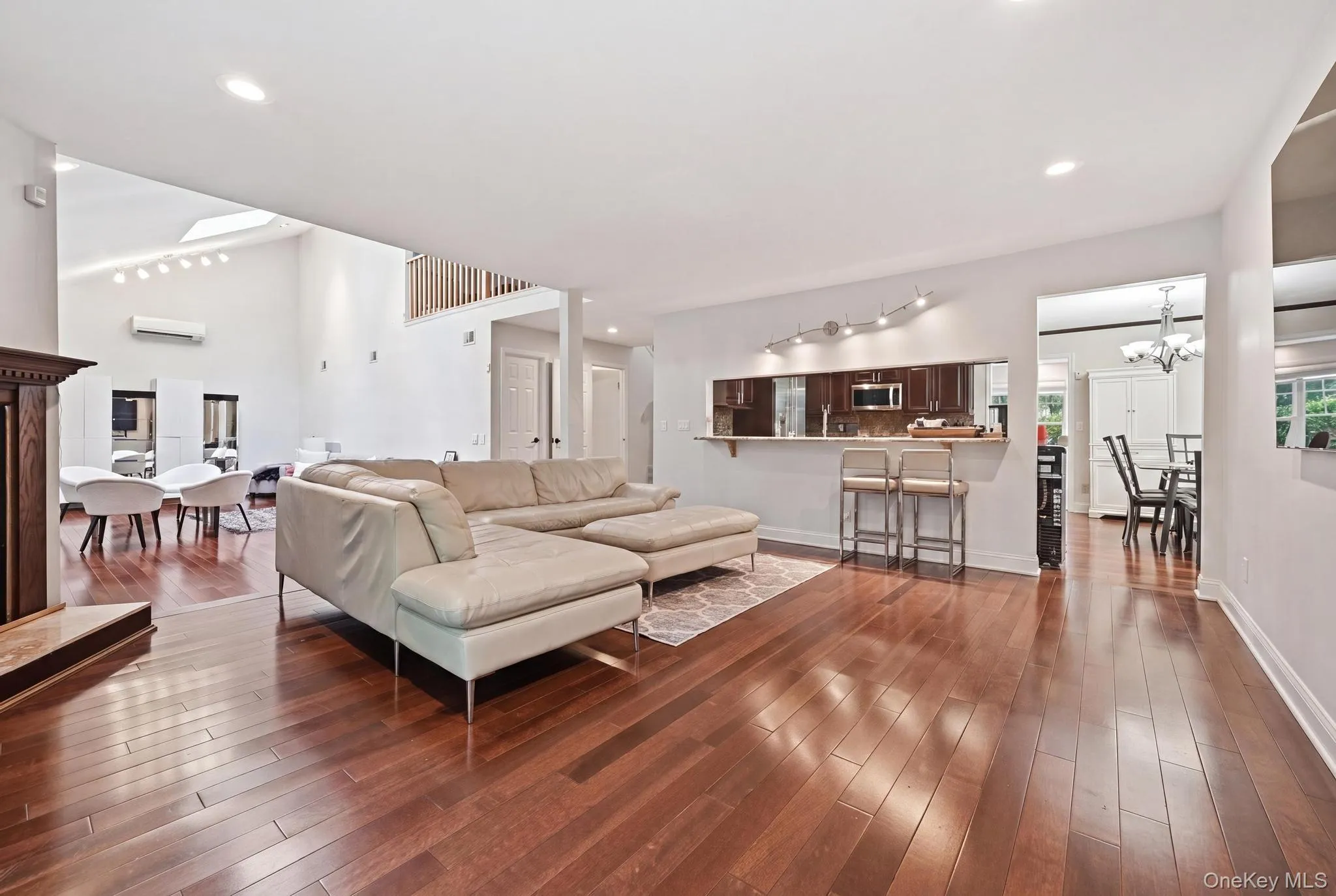 Hardwood flooring throughout a living space featuring a fireplace with a wood mantle Hardwood flooring throughout a living space featuring a fireplace with a wood mantle