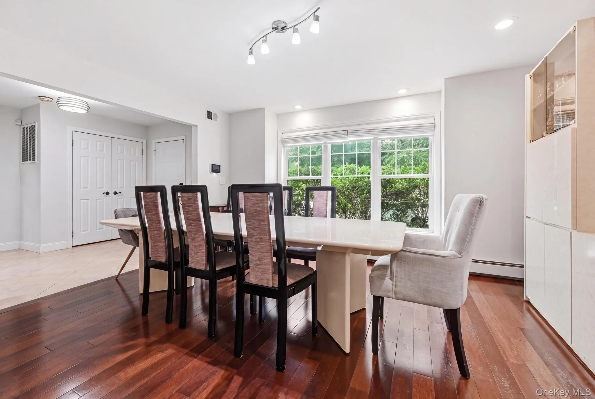 Dining area featuring rich wood-finish flooring, a contemporary light fixture, and a large window offering exterior scenery Dining area featuring rich wood-finish flooring, a contemporary light fixture, and a large window offering exterior scenery