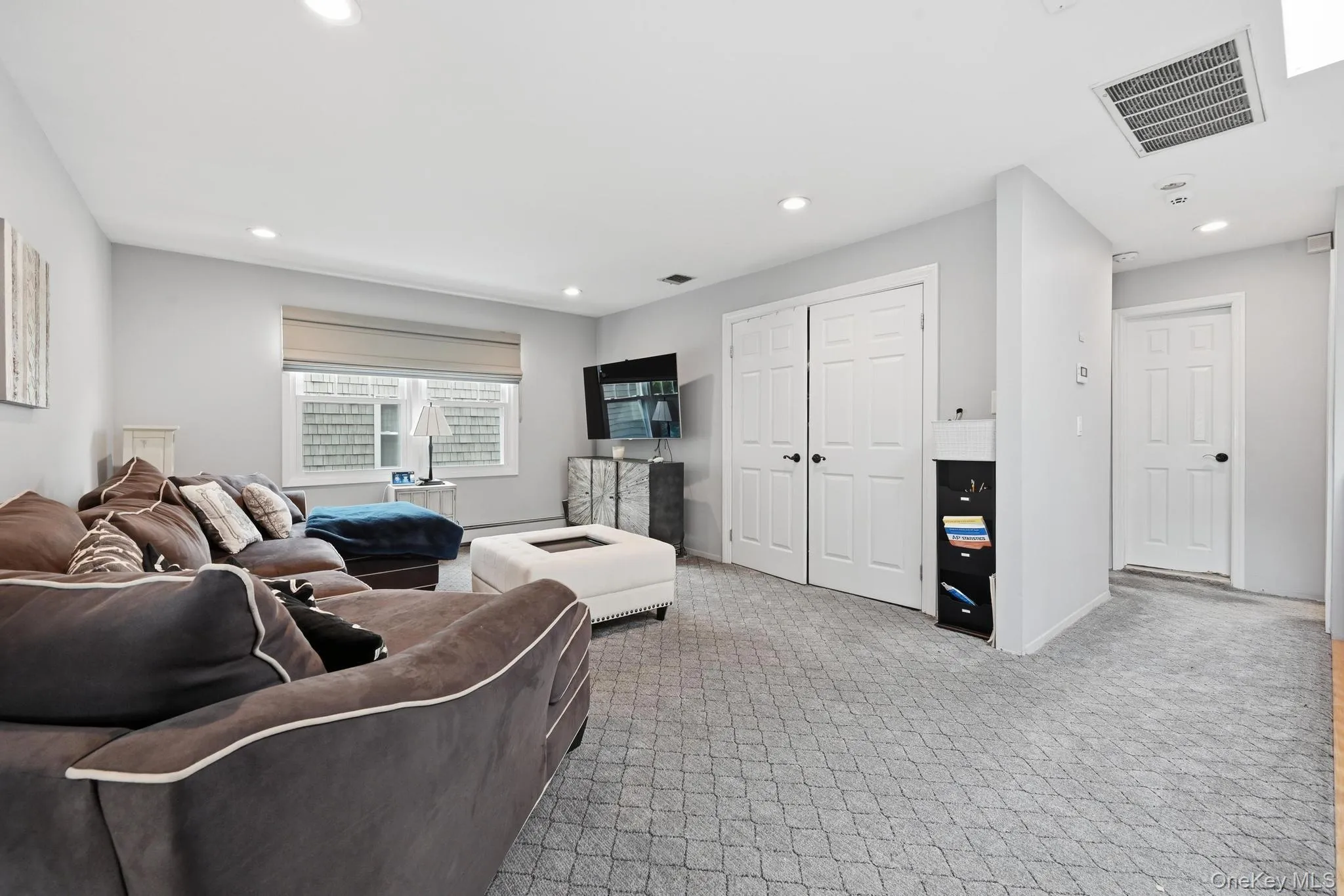 Living area on the second floor featuring light gray walls, recessed lighting, patterned carpet flooring, a window with a neutral shade, and white paneled doors Living area on the second floor featuring light gray walls, recessed lighting, patterned carpet flooring, a window with a neutral shade, and white paneled doors