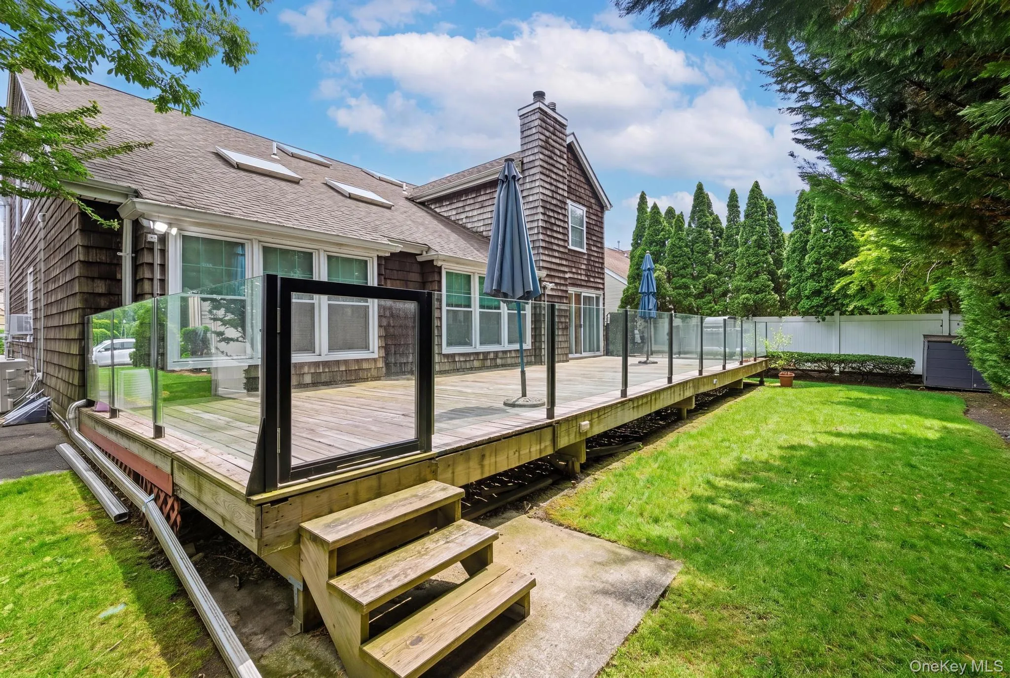 A spacious deck featuring sleek tempered glass railings, creating a modern outdoor retreat with unobstructed views A spacious deck featuring sleek tempered glass railings, creating a modern outdoor retreat with unobstructed views