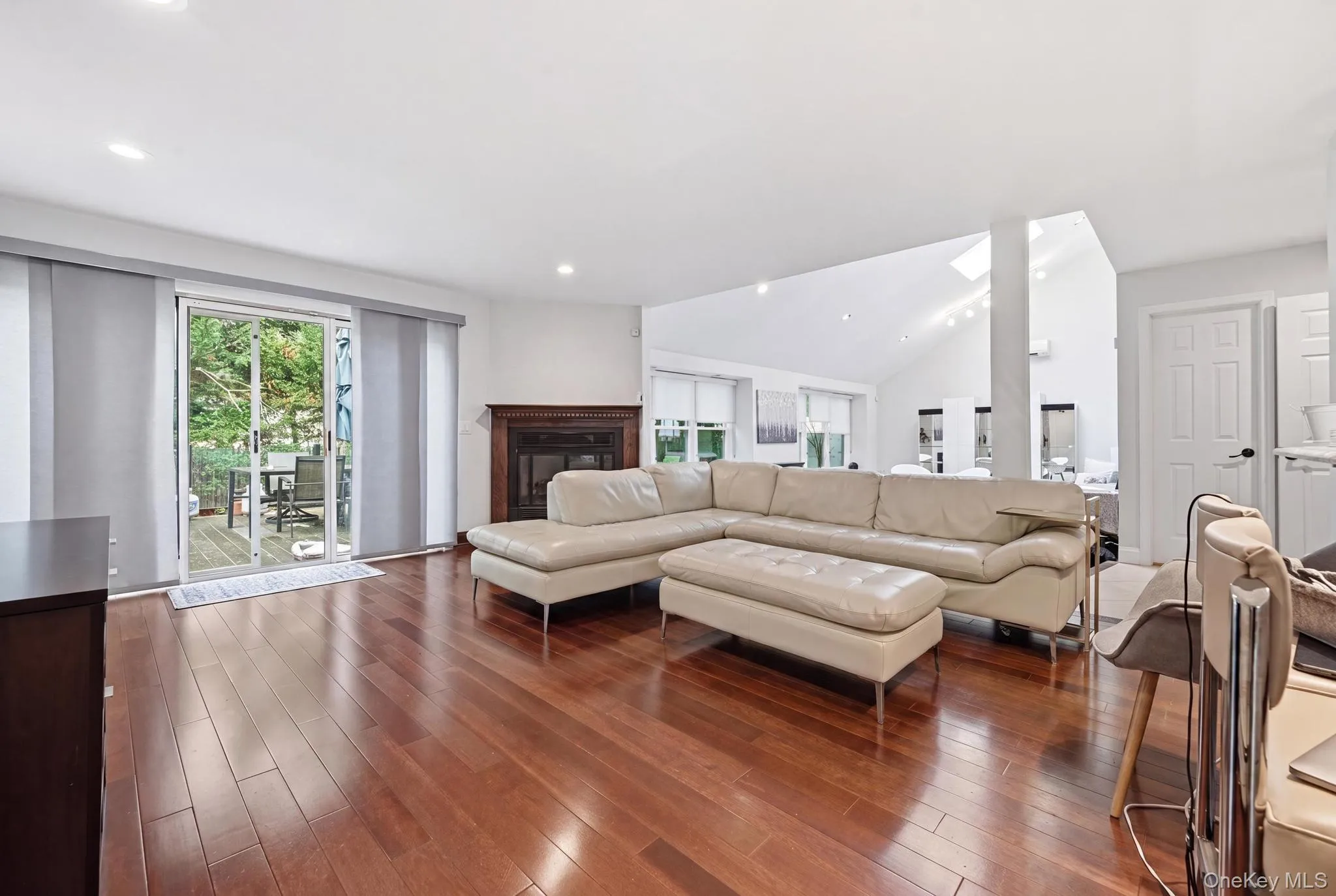 Hardwood flooring throughout a living space featuring a fireplace with a wood mantle Hardwood flooring throughout a living space featuring a fireplace with a wood mantle