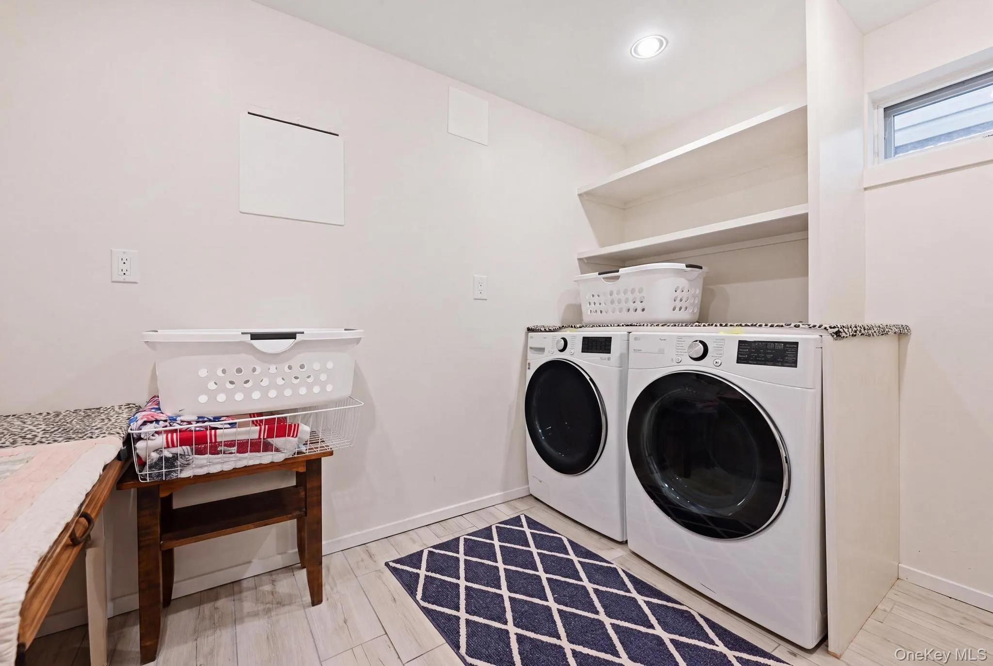 Dedicated laundry area featuring a granite-look countertop, integrated shelving, and light wood-finish flooring Dedicated laundry area featuring a granite-look countertop, integrated shelving, and light wood-finish flooring