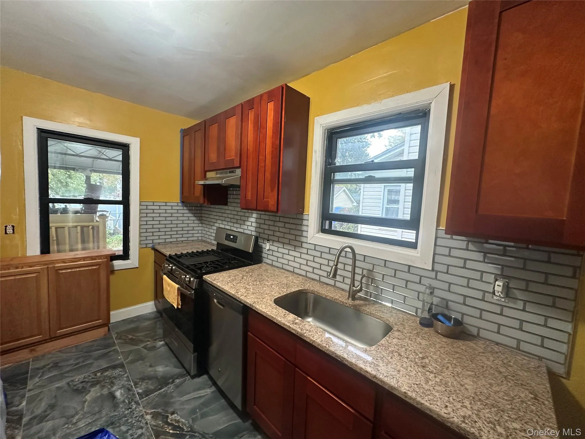 Kitchen with tasteful backsplash, stainless steel appliances, dark marble finish flooring, light stone countertops, and plenty of natural light Kitchen with tasteful backsplash, stainless steel appliances, dark marble finish flooring, light stone countertops, and plenty of natural light