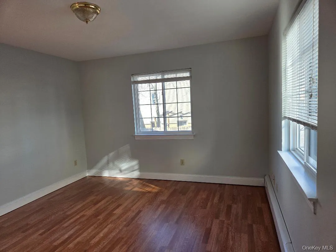 Spare room with dark wood-style flooring, a baseboard radiator, and baseboards Spare room with dark wood-style flooring, a baseboard radiator, and baseboards