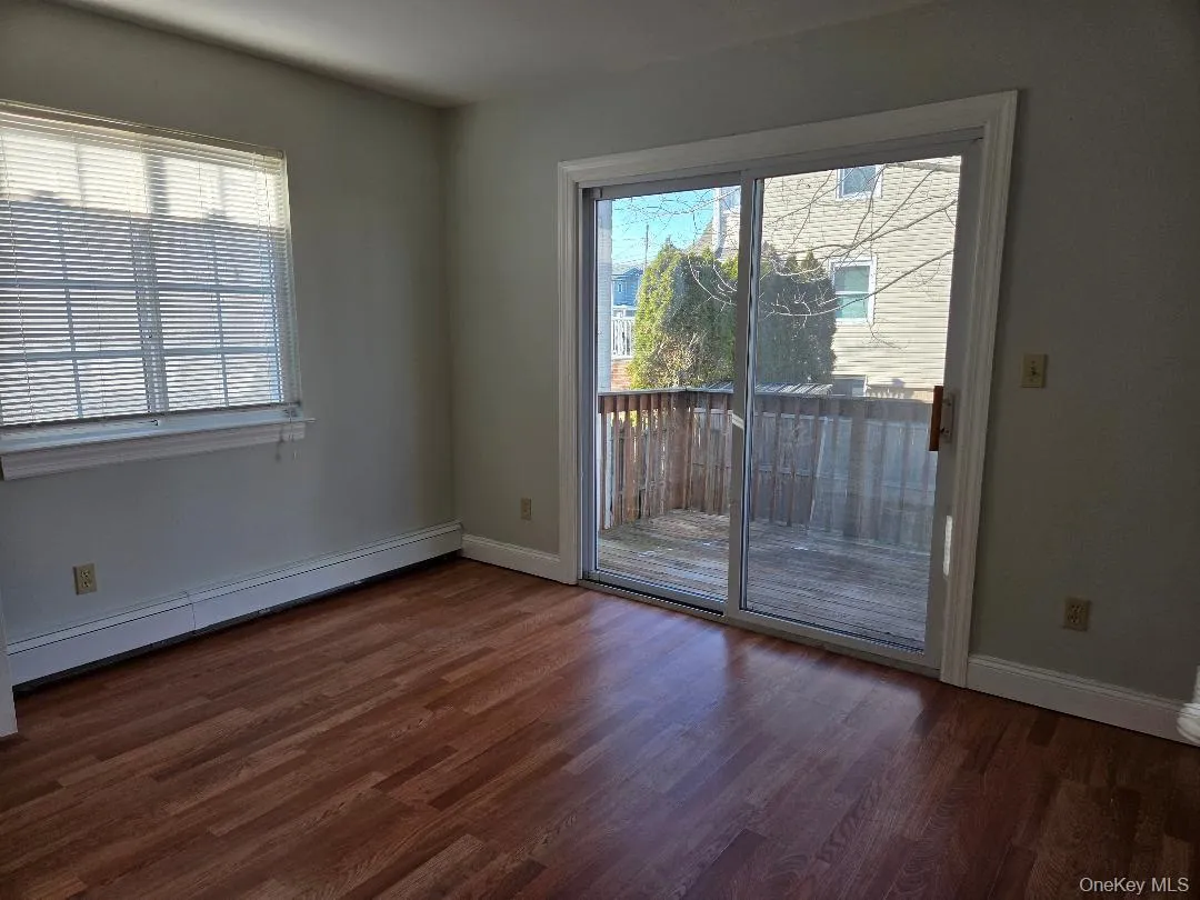 Spare room with dark wood-type flooring, a baseboard radiator, and baseboards Spare room with dark wood-type flooring, a baseboard radiator, and baseboards